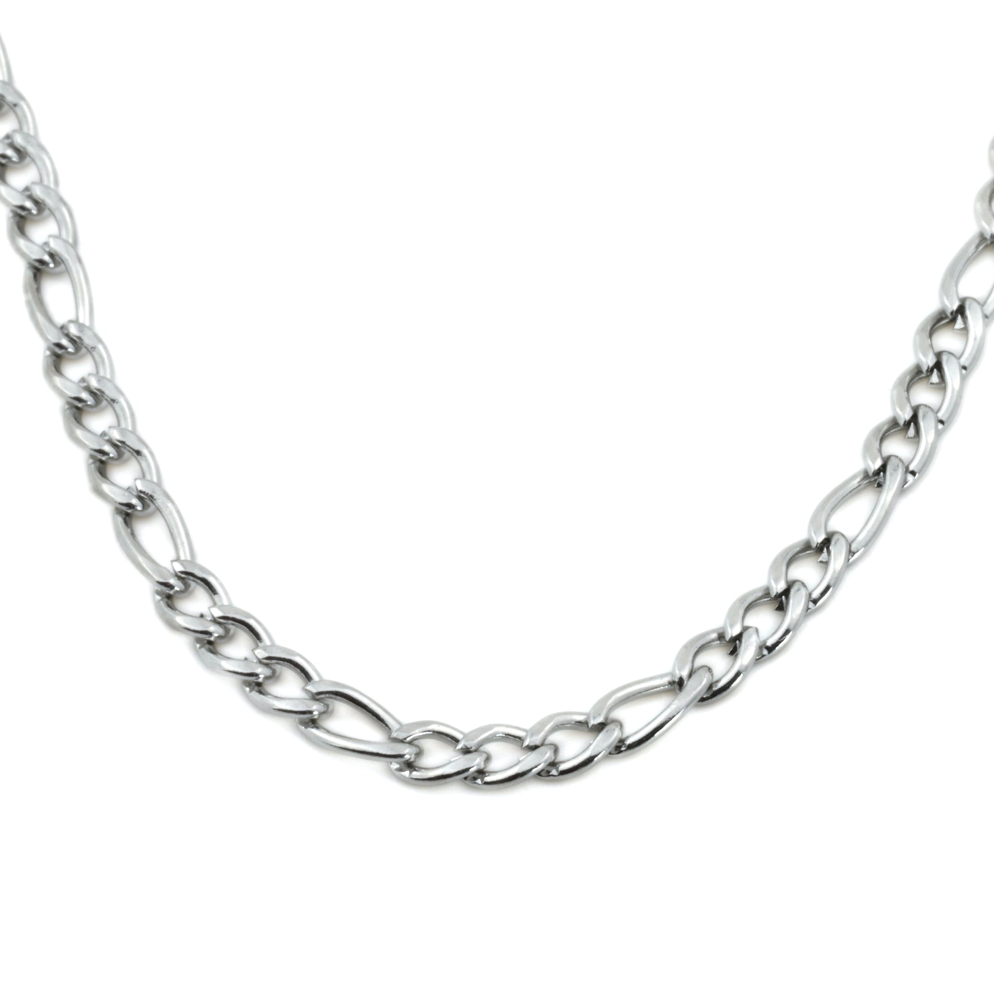 Close up view of silver figaro necklace showing alternating big an small links on a white background