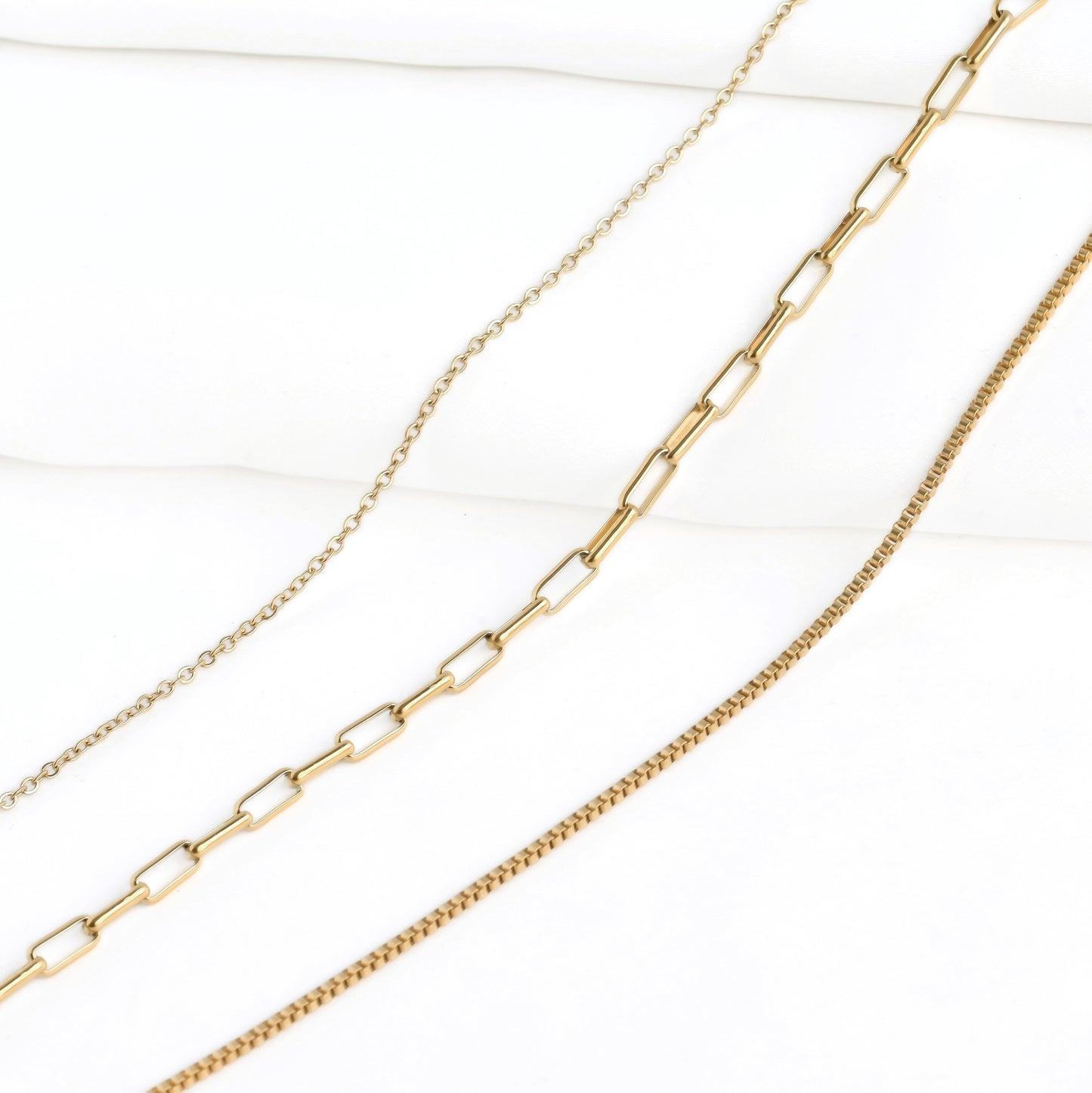Three gold chains, cable, small paperclip and box,  on a white background