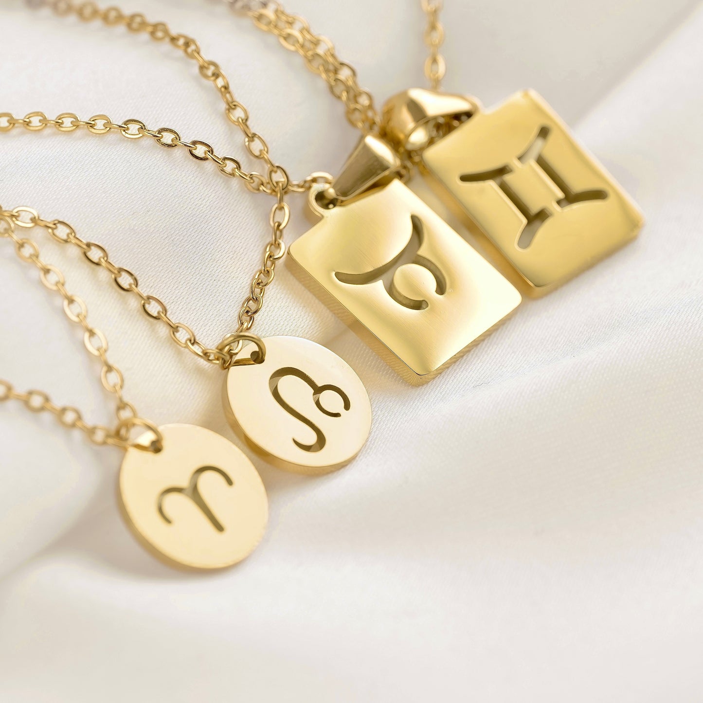 Gold necklaces with zodiac symbols on a white background