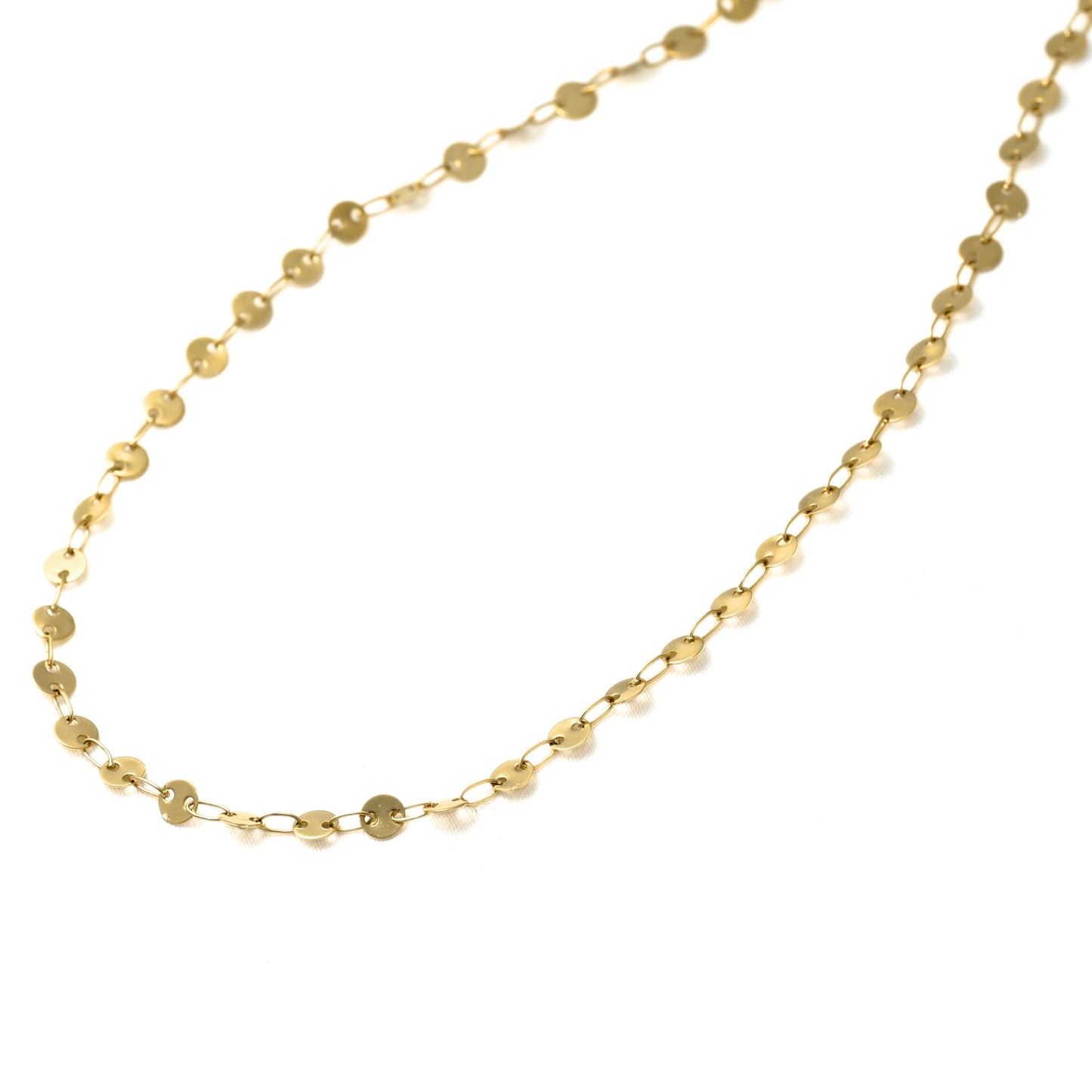 A delicate gold chain necklace featuring small, flat circular disc links, displayed on a clean white background.