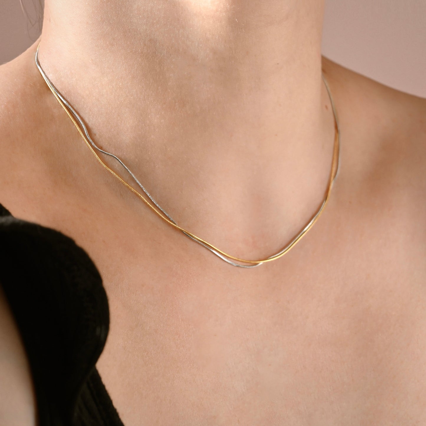 Two-tone necklace on a person against a neutral background