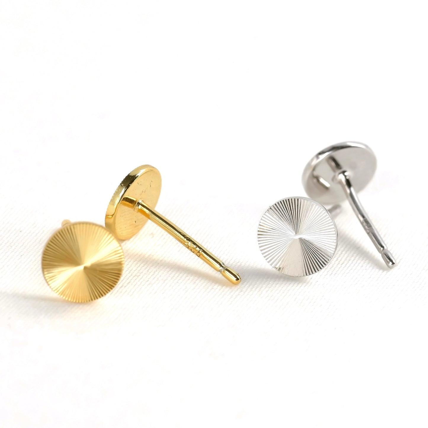 Gold and silver circular earrings with textured surface on a white background