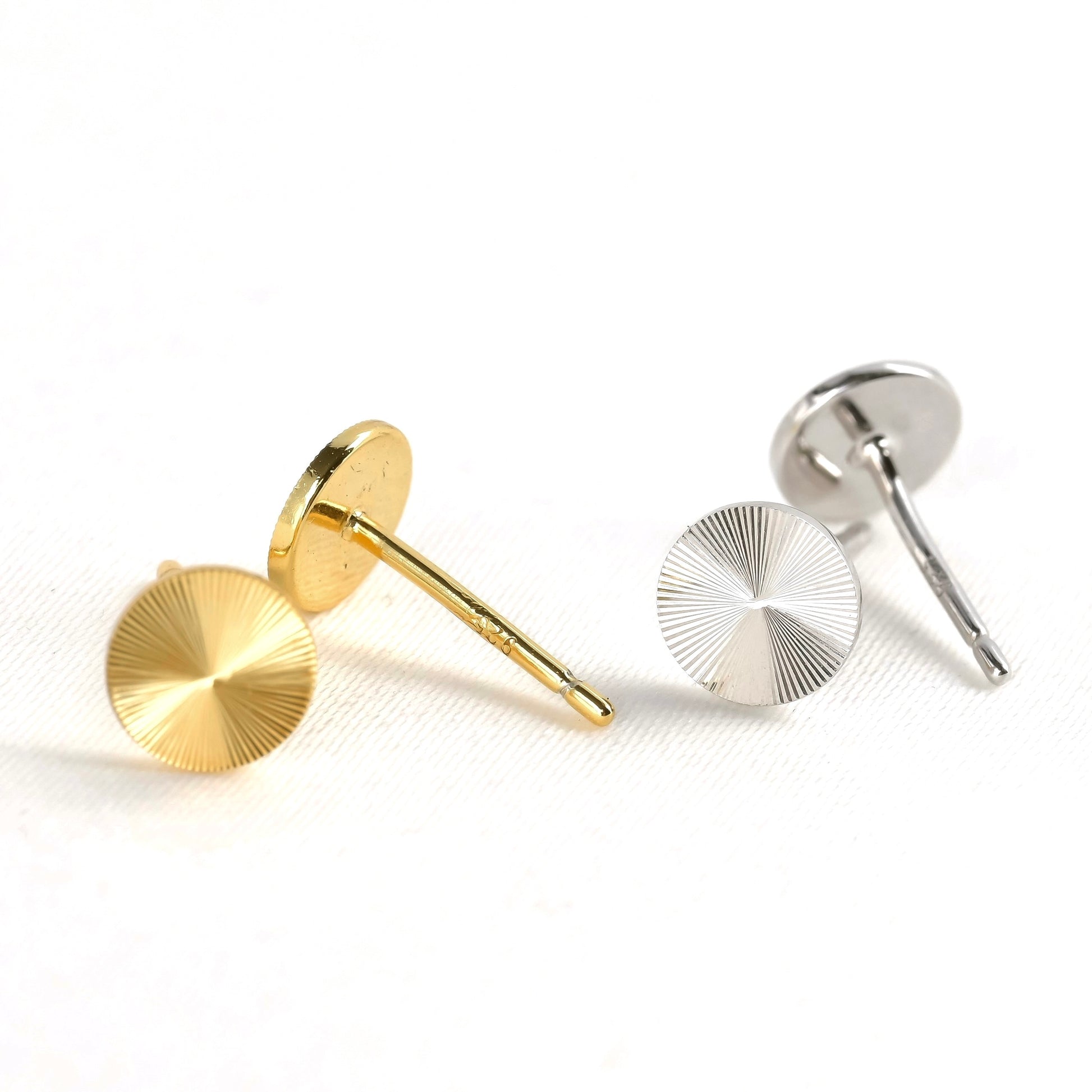 Gold and silver circular earrings with textured surface on a white background
