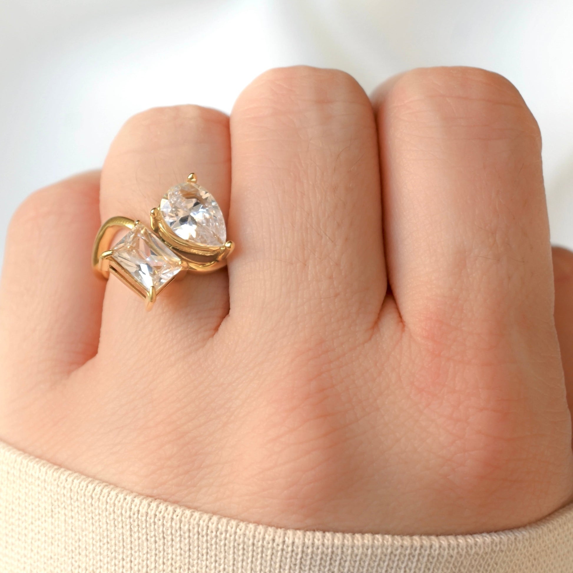 18k Gold ring with twolarge diamonds on a person's finger against a white background