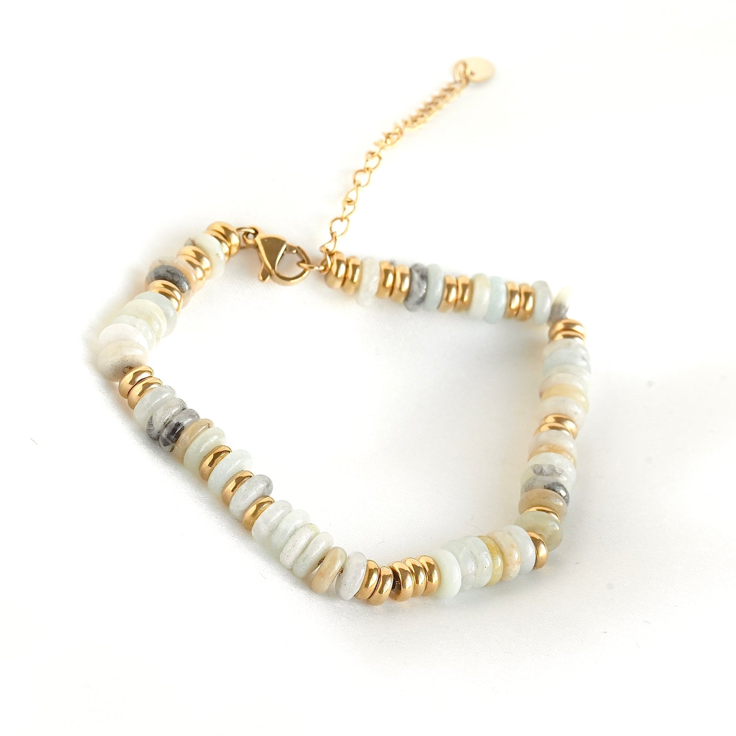 A beaded bracelet featuring light gray and white stone beads alternating with small gold metal spacers and a gold clasp, displayed on a clean white background.