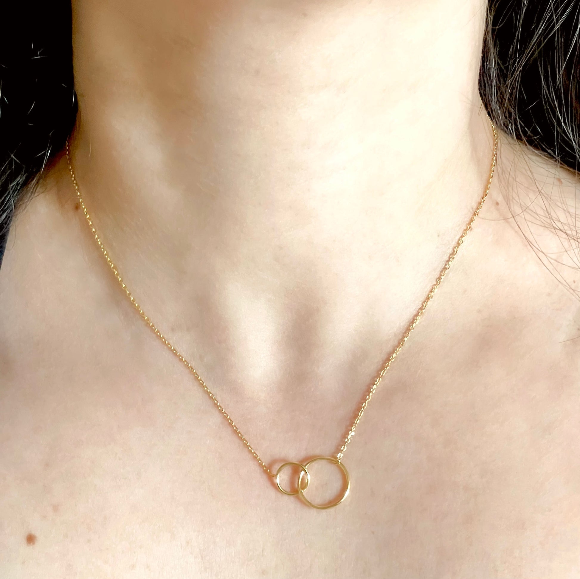 Gold necklace with interlocking rings worn by a person