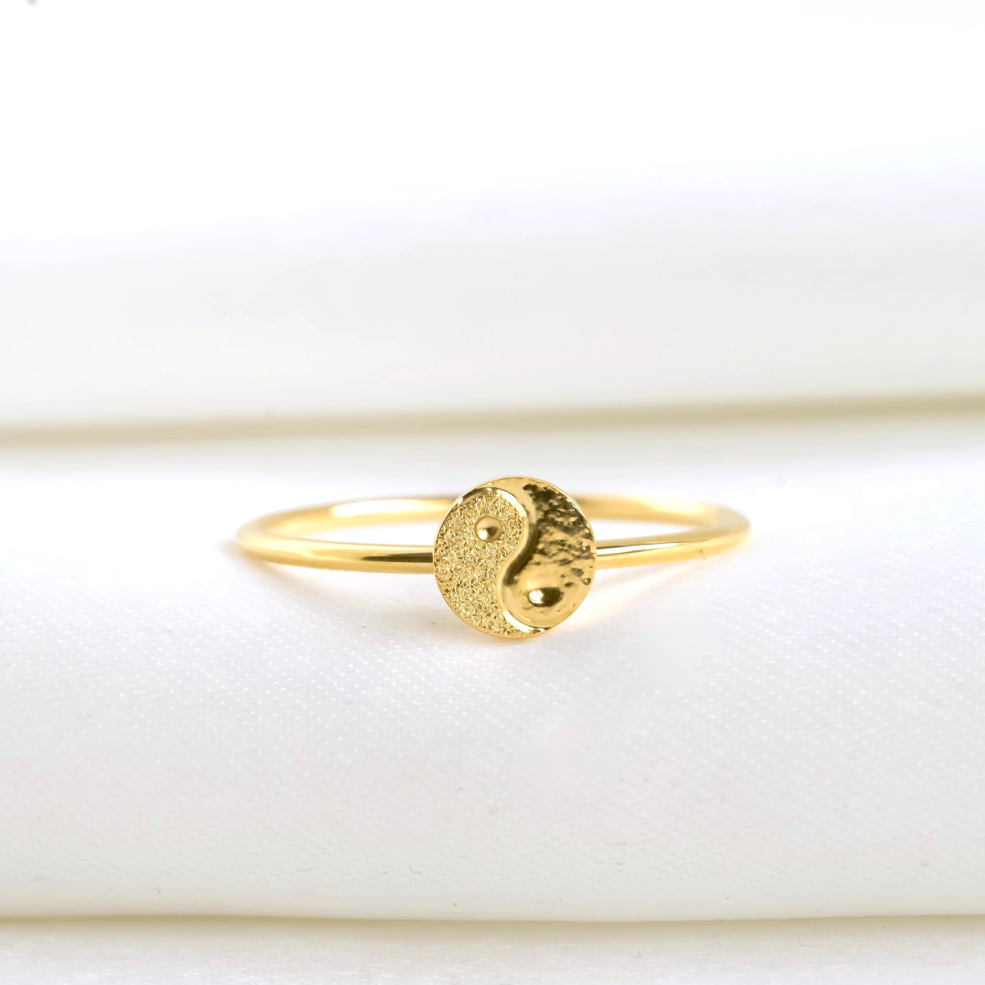 Front view: Gold ring with a yin yang symbol on a white background