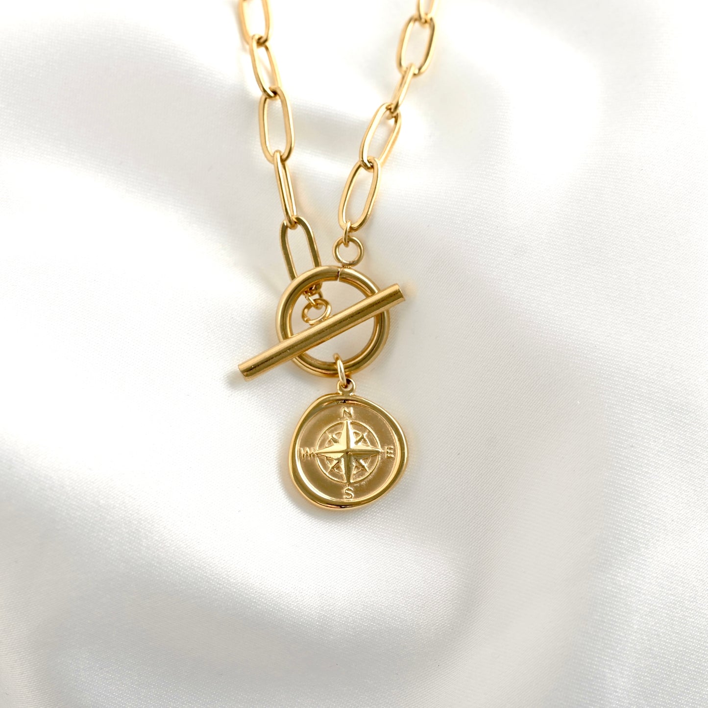Gold necklace with a compass pendant on a white background