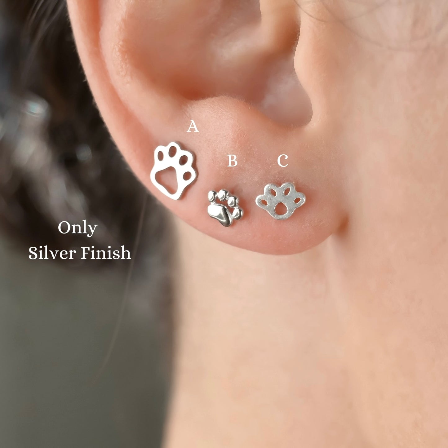 Three silver paw print earrings displayed on an ear with 'Only Silver Finish' text.