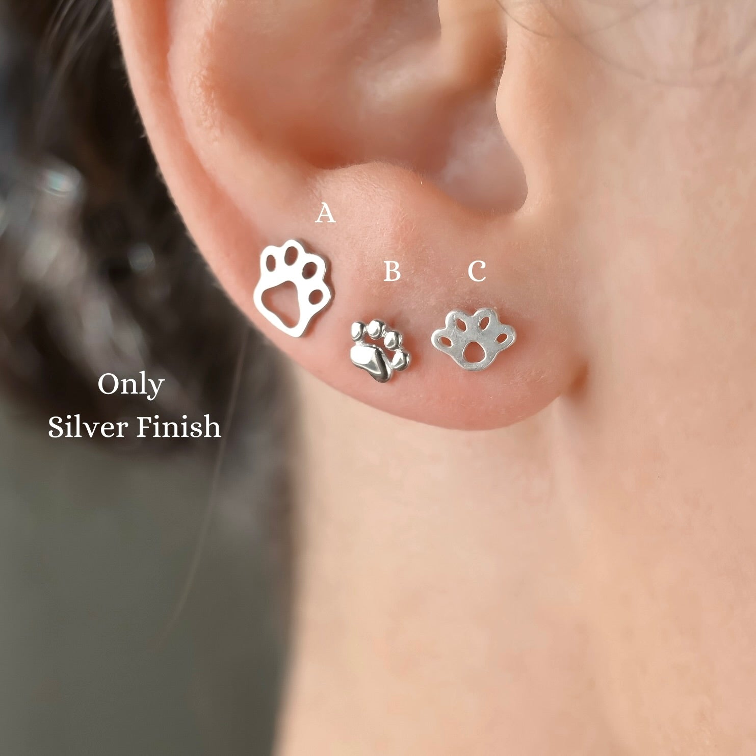 Three silver paw print earrings displayed on an ear with 'Only Silver Finish' text.