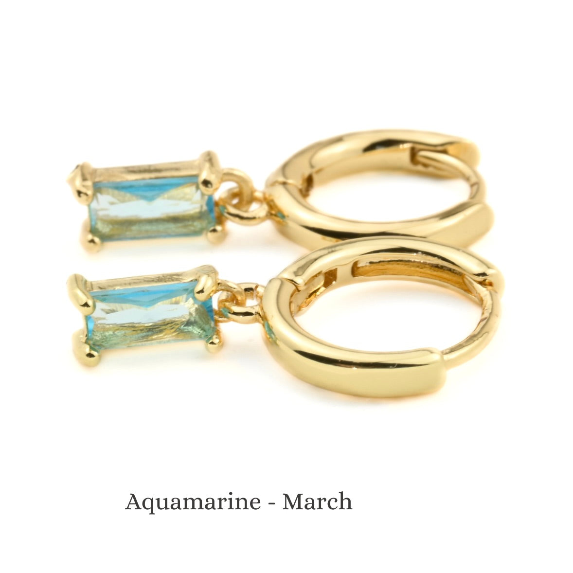 Gold hoop earrings with aquamarine gemstones on a white background