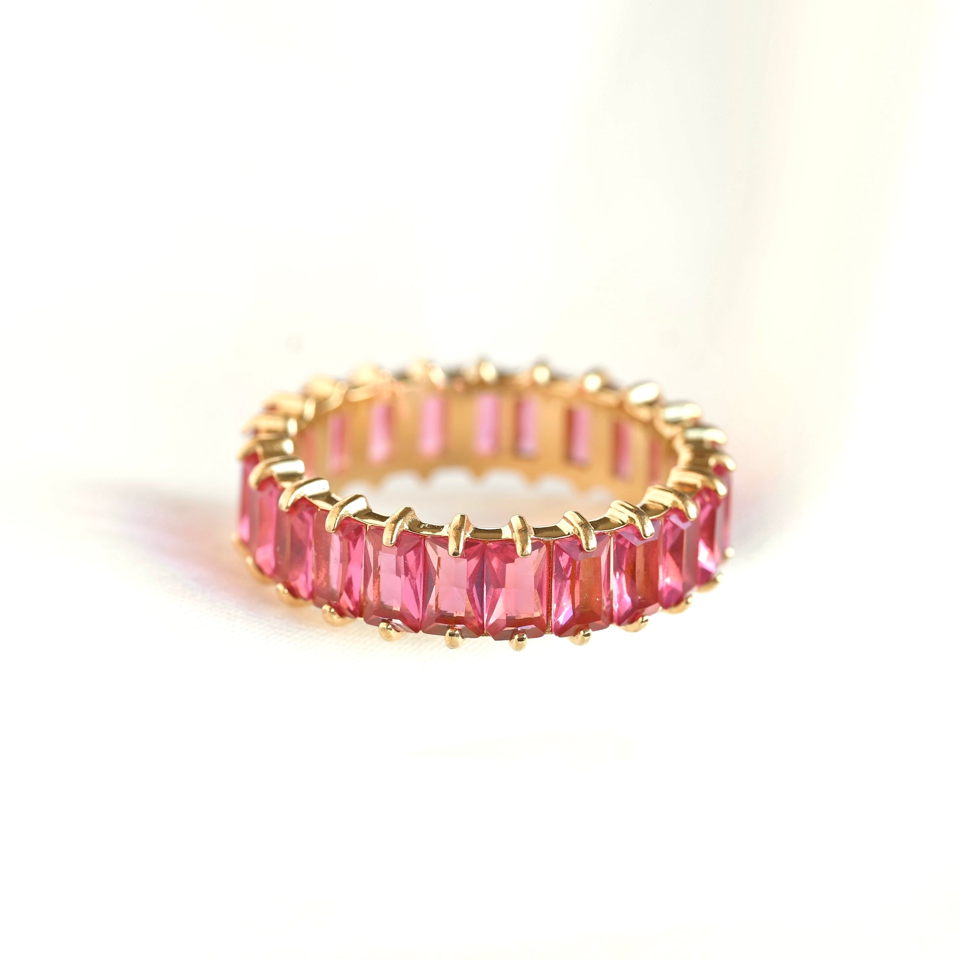 Gold ring with ruby gemstones on a white background
