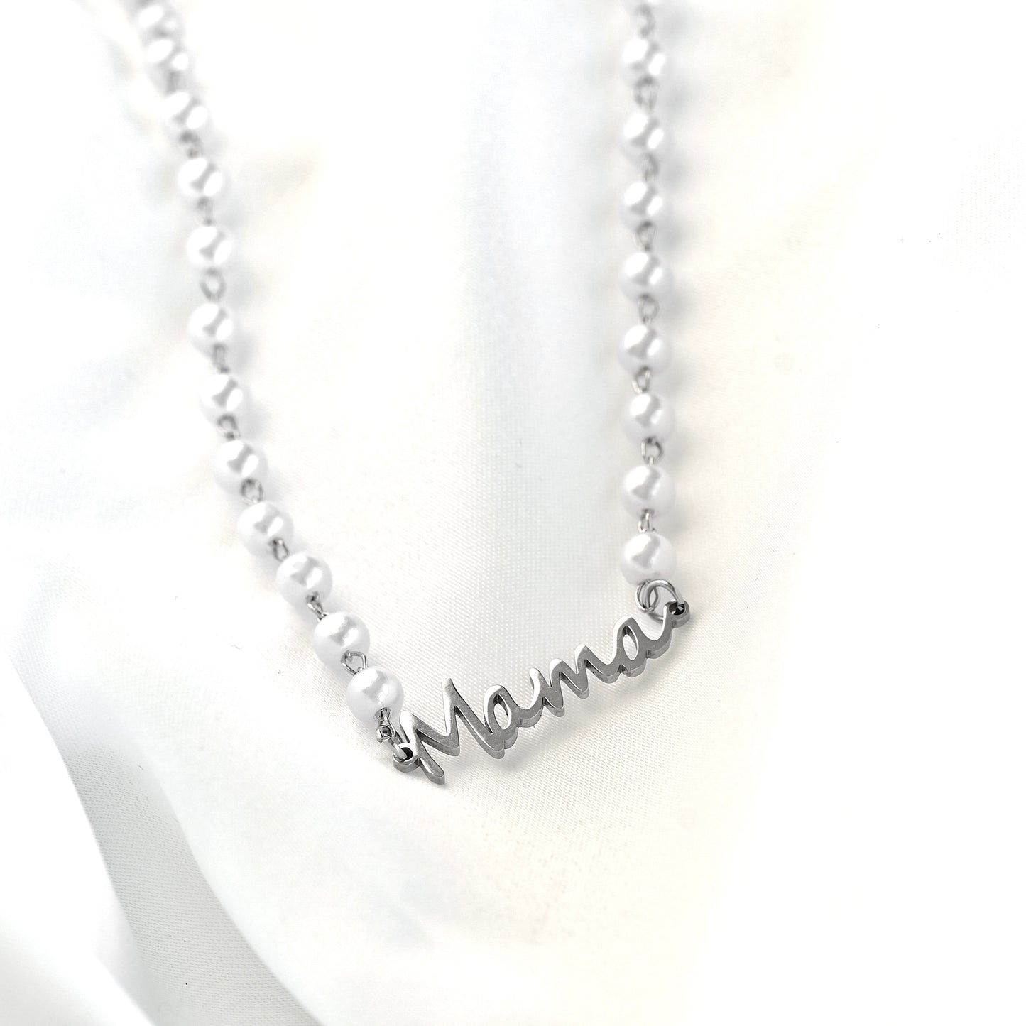 Silver necklace with 'mama' pendant on a white background
