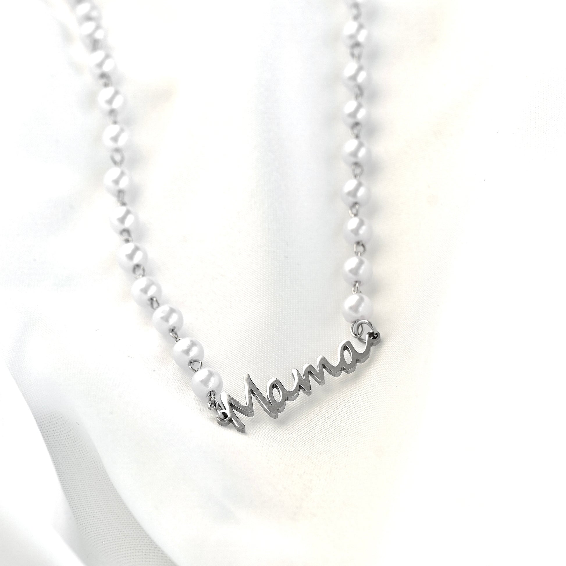 Silver necklace with 'mama' pendant on a white background