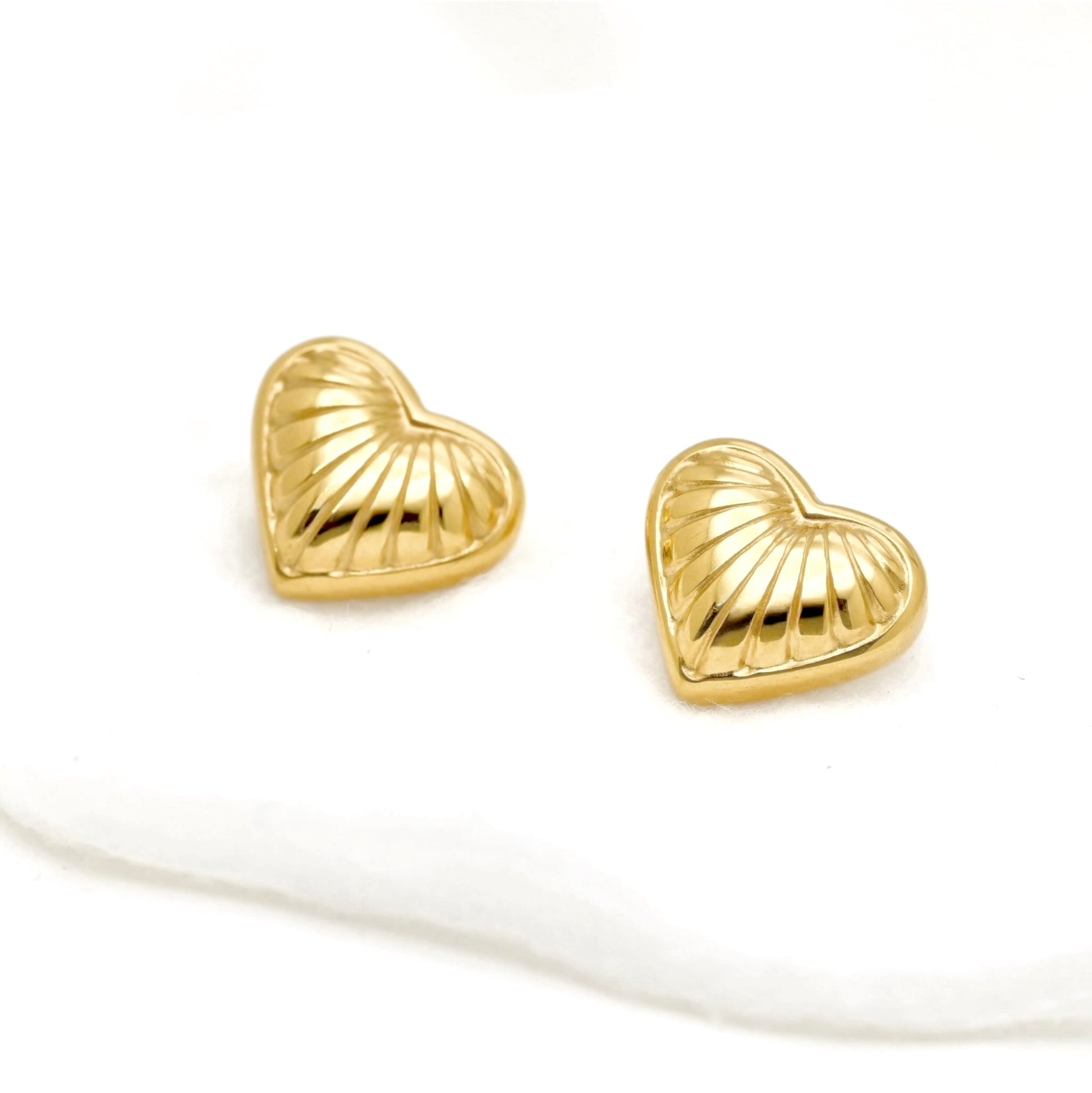 A pair of small gold heart-shaped stud earrings with a textured, ribbed surface, displayed on a clean white background.