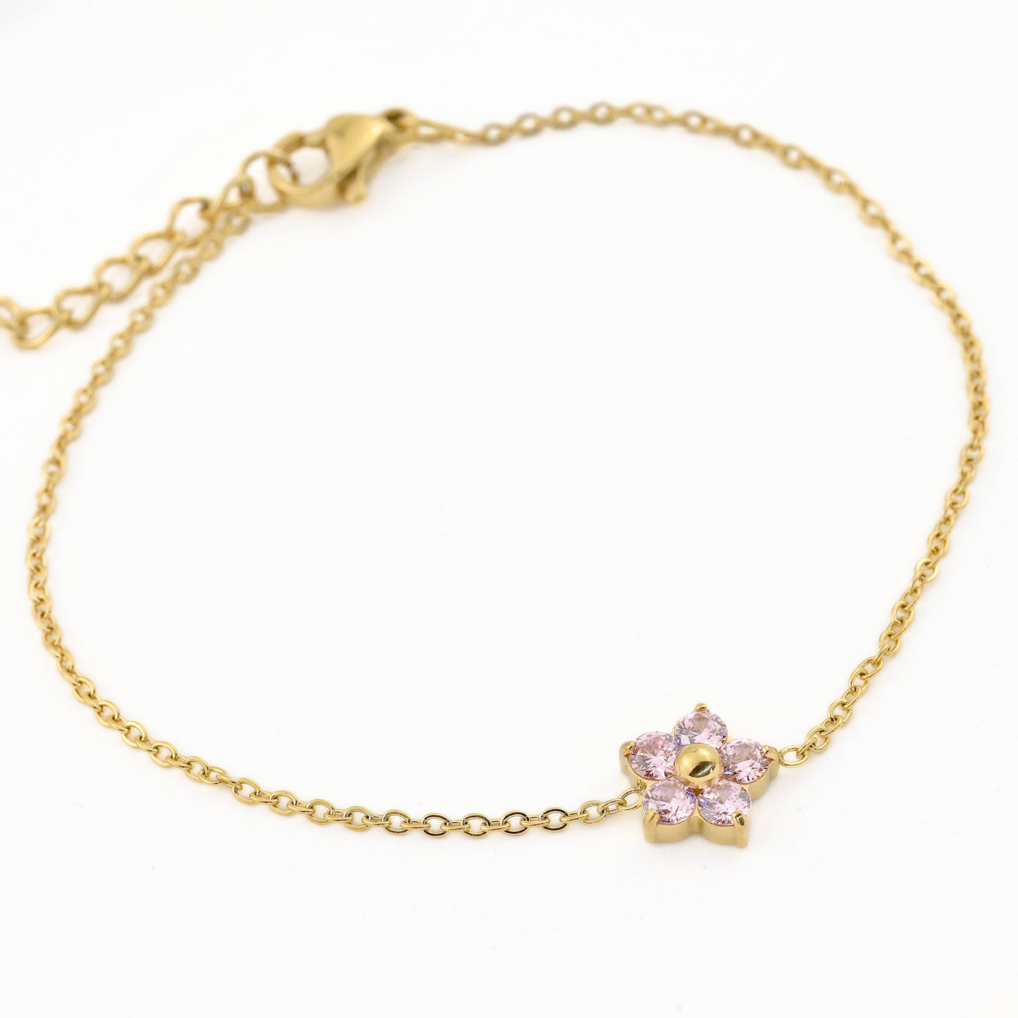 Gold bracelet with a pink flower charm on a white background