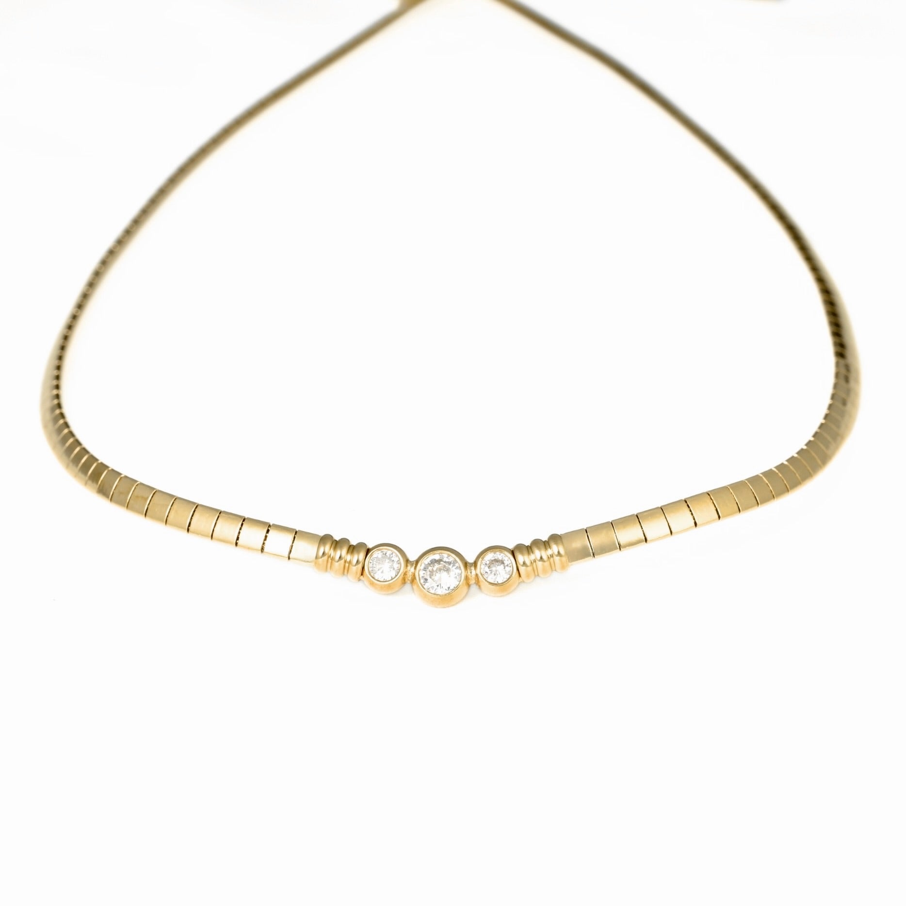 A gold snake chain necklace featuring three small clear round-cut gemstones set in a row at the center, photographed against a solid white background.