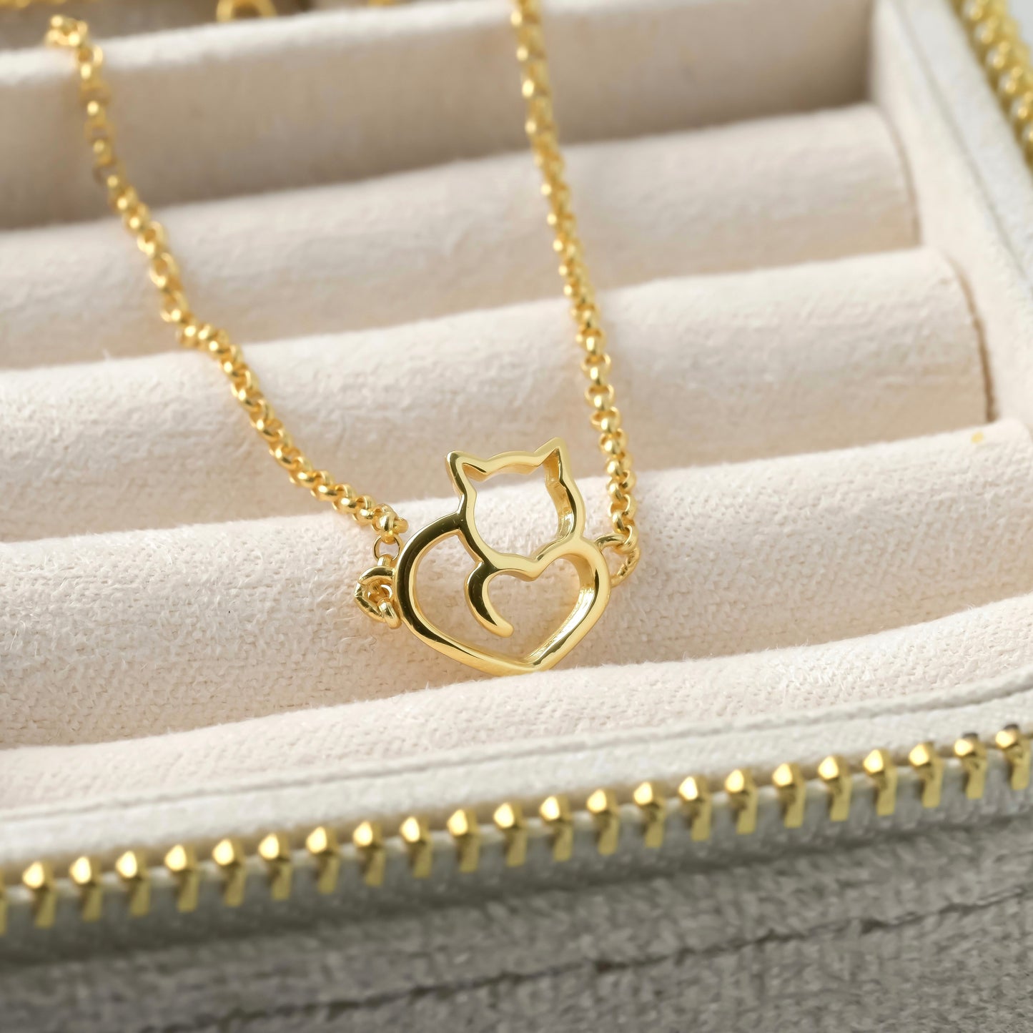 Gold bracelet with a cat heart pendant on a textured surface