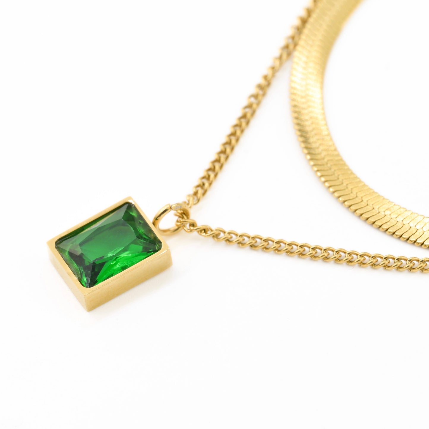 Close up view of the rectangle emerald green stone pendant in a gold frame.