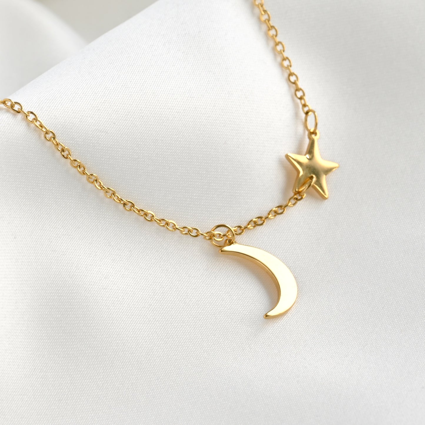 Gold necklace with a star charm and crescent moon pendant on a white background