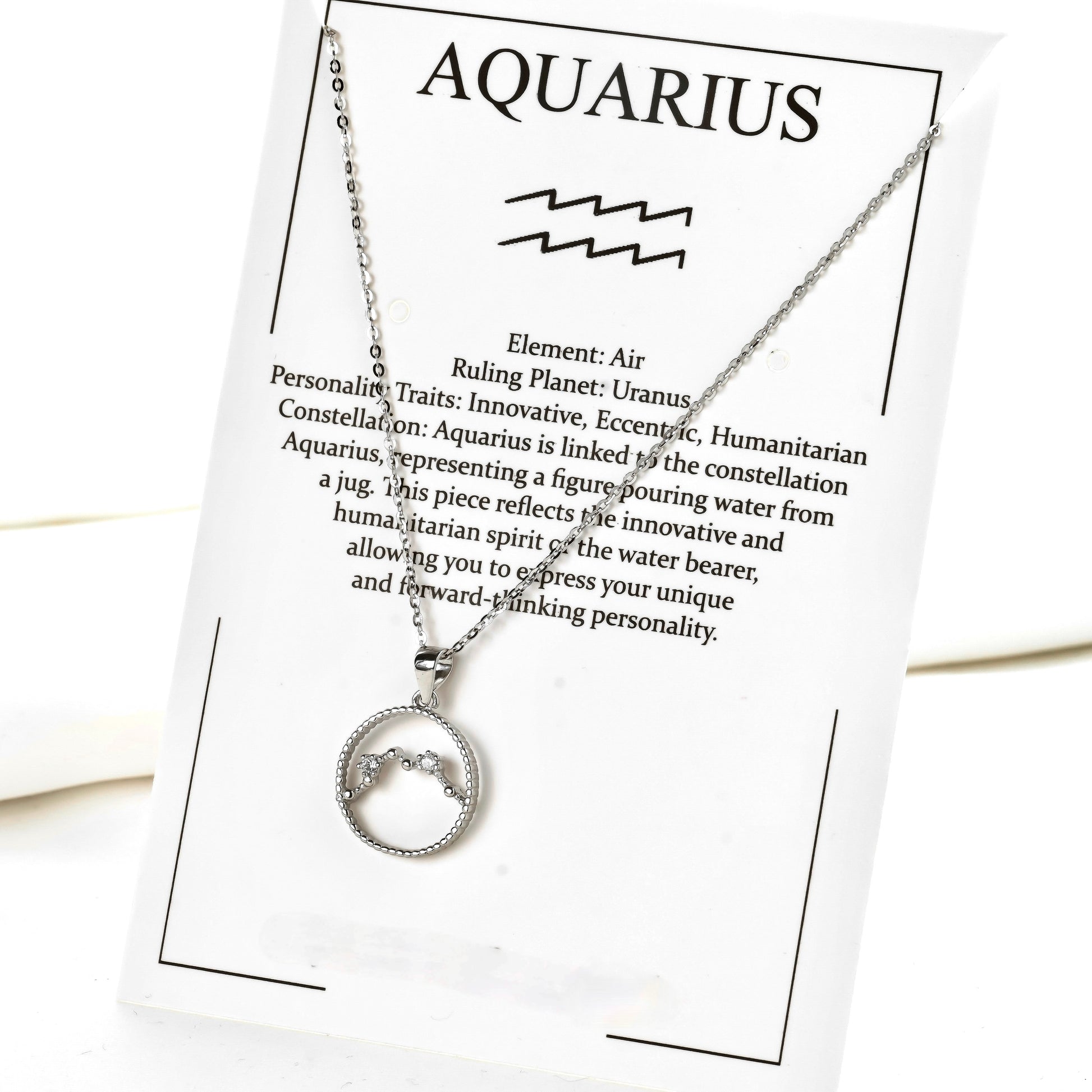 Silver necklace with a circular pendant on an Aquarius-themed card.