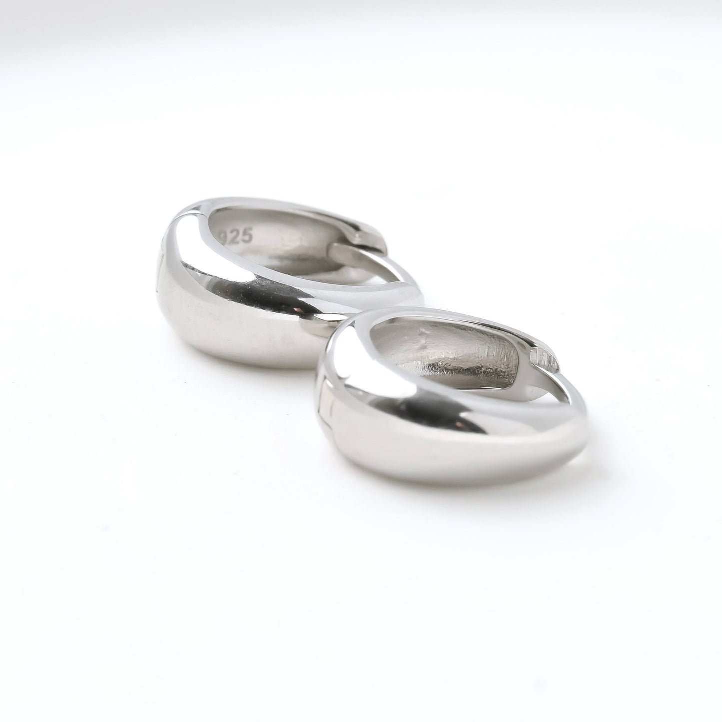 Pair of tiny chunky silver hoop earrings on a white background