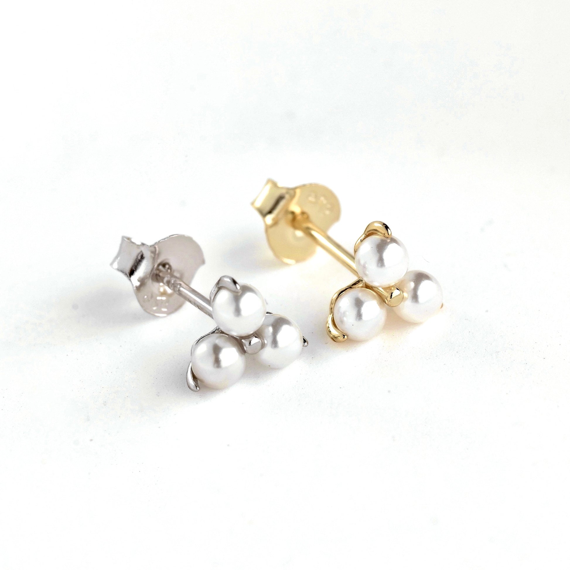 Pair of pearl stud earrings, one gold and one silver, on a white background
