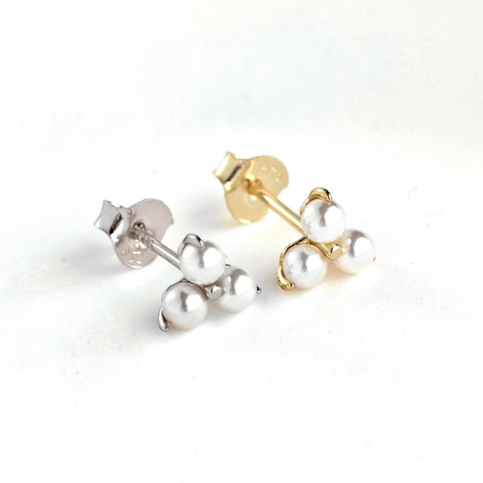 Pair of pearl stud earrings, one gold and one silver, on a white background