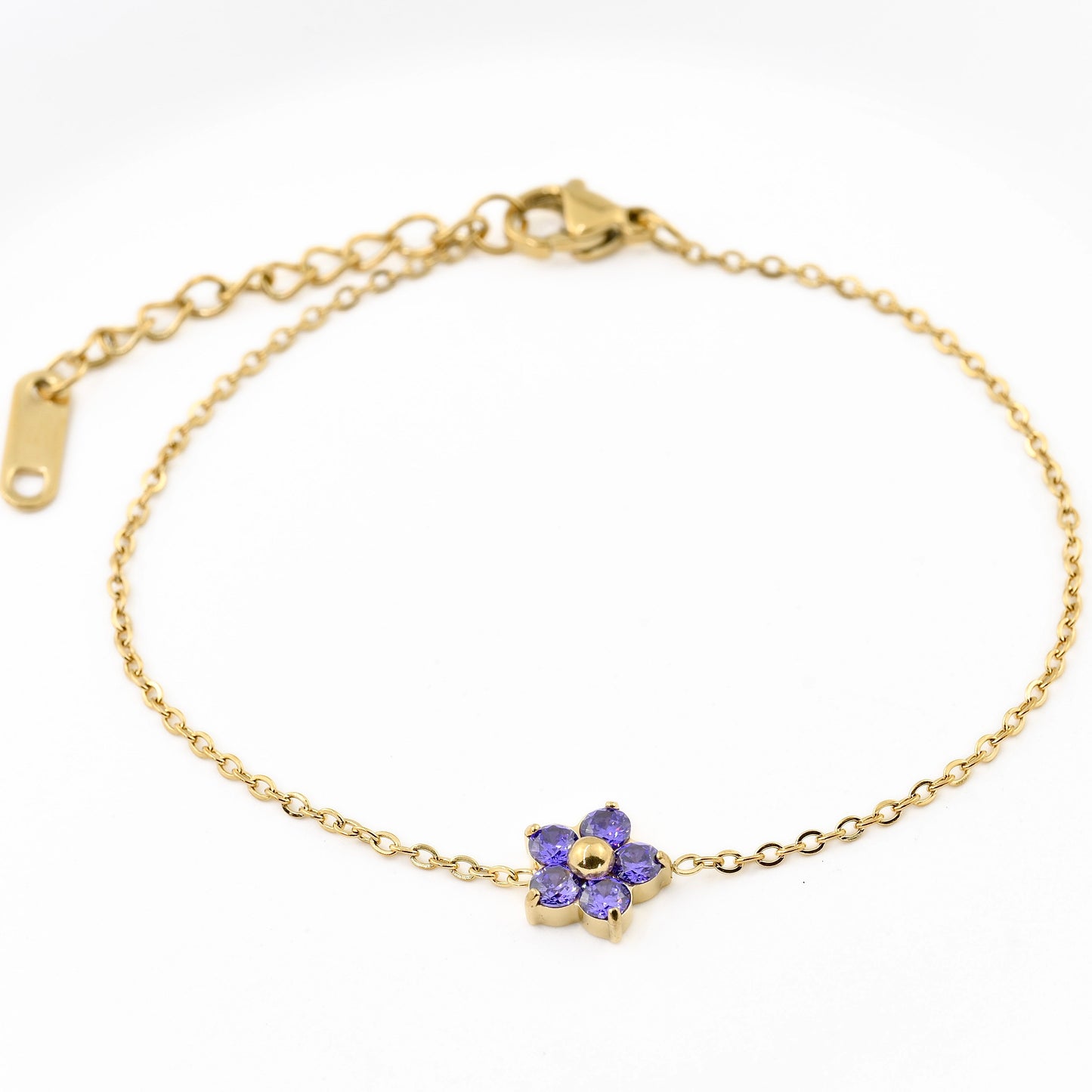 Gold bracelet with a purple flower charm on a white background