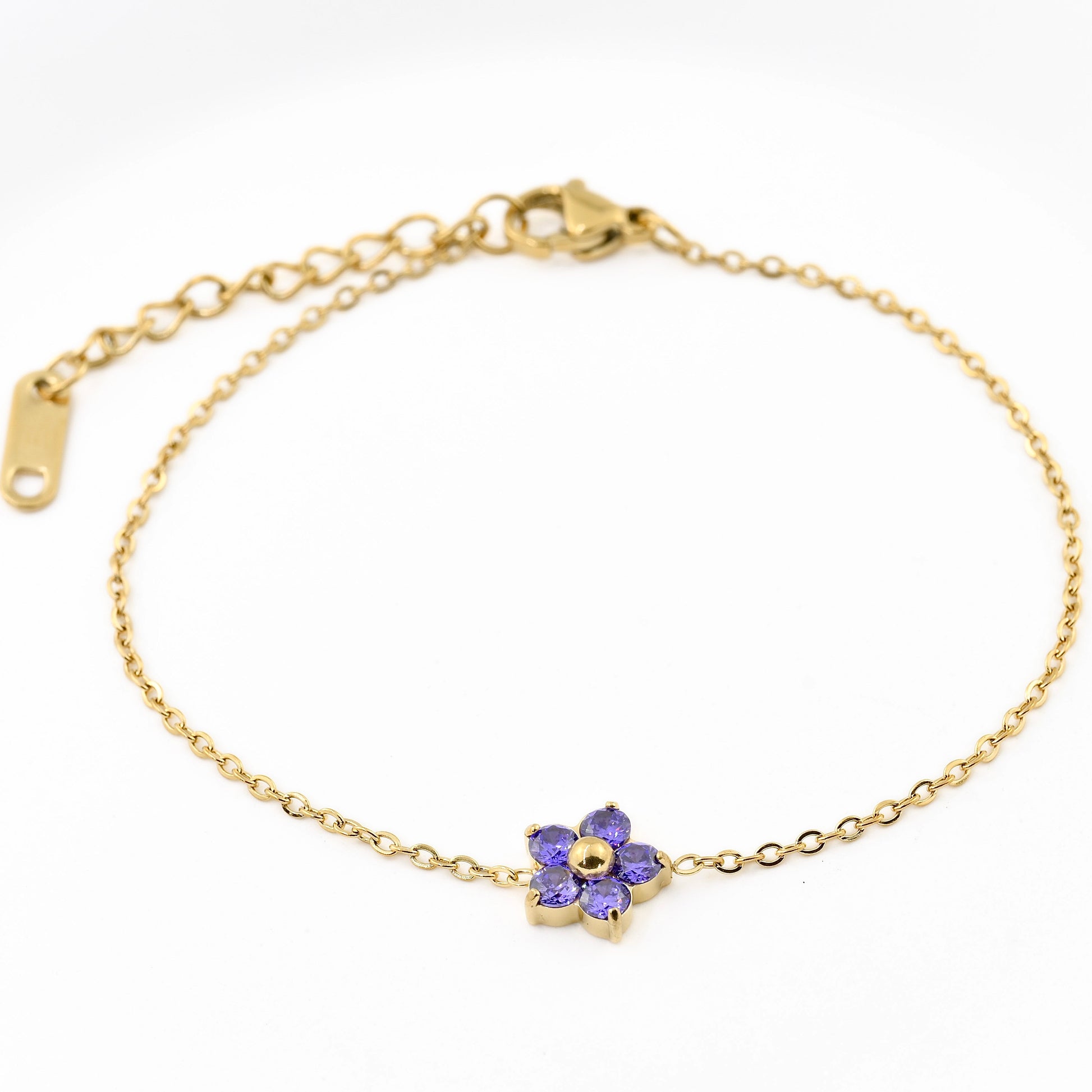 Gold bracelet with a purple flower charm on a white background