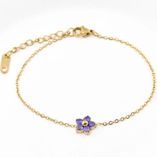 Gold bracelet with a purple flower charm on a white background