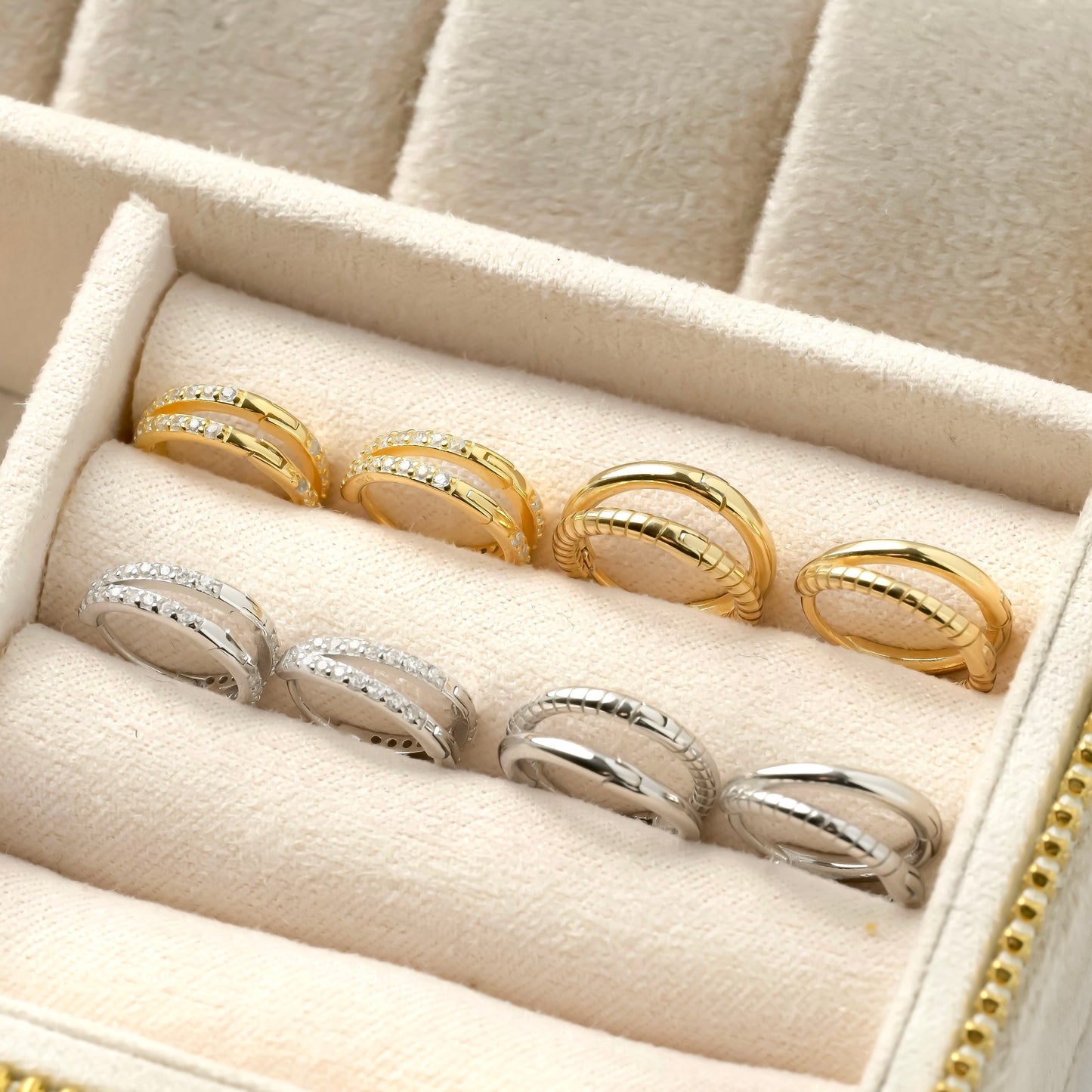 Set of four gold and silver layered huggie earrings in a jewelry box