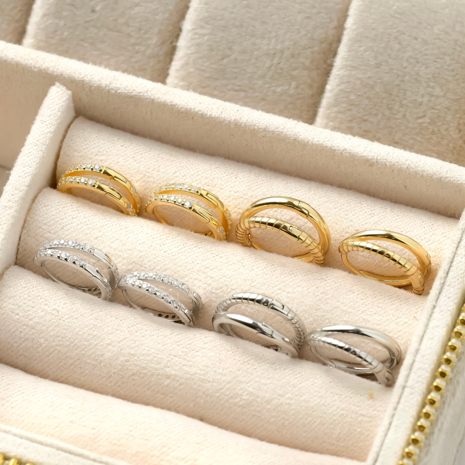 Set of four gold and silver layered huggie earrings in a jewelry box