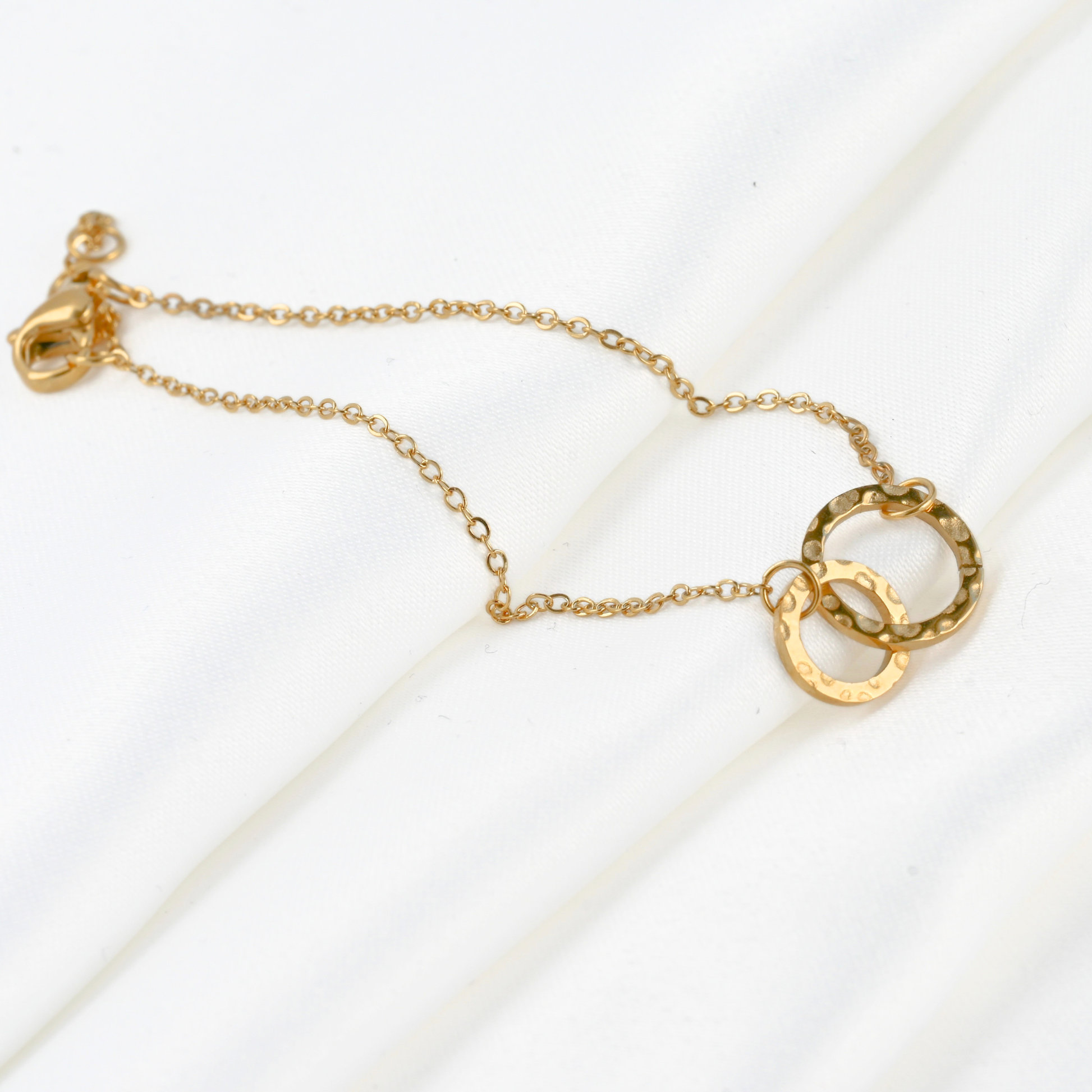 Gold interlocking circle bracelet with a small and medium sized textured circles 