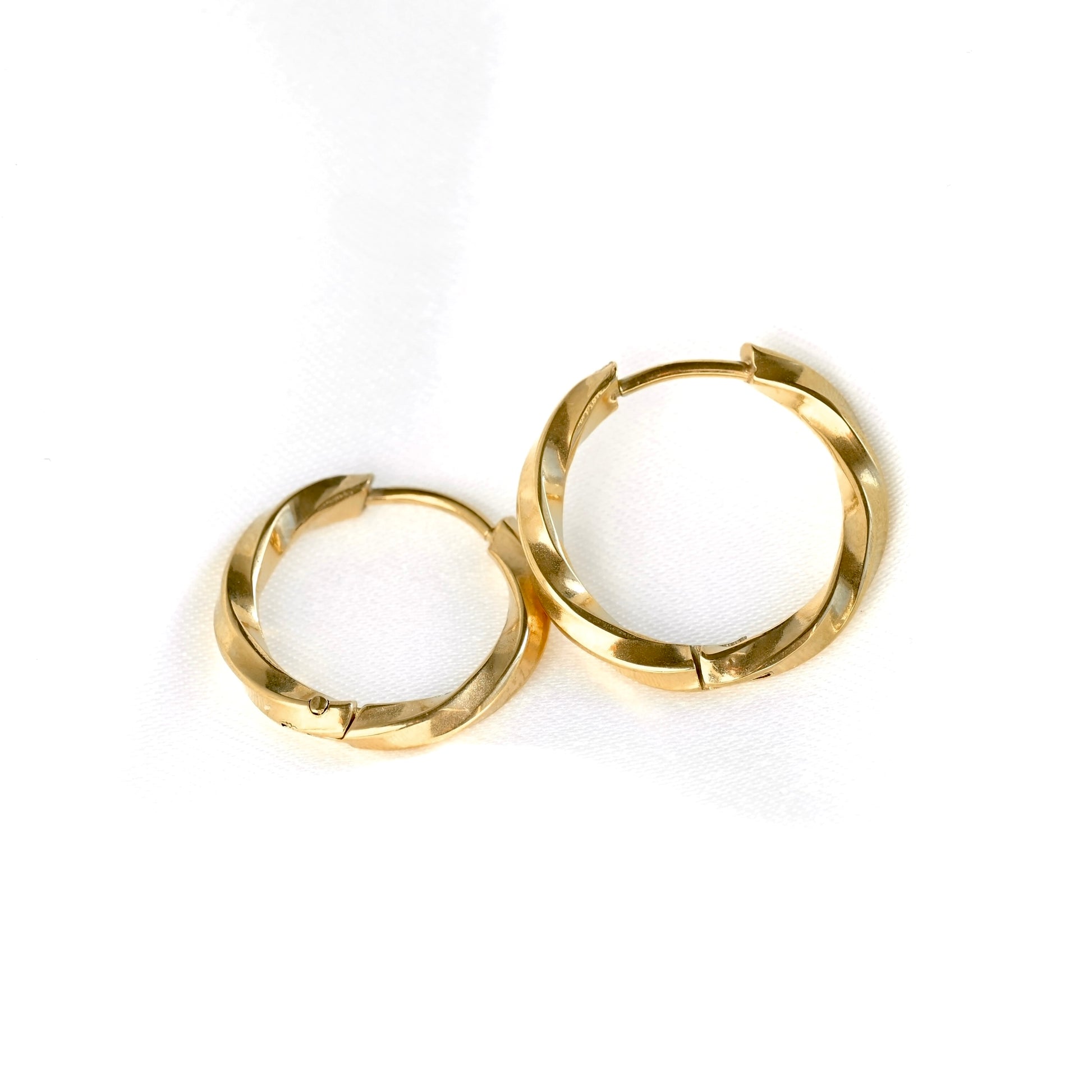A pair of gold huggie hoop earrings with a textured, faceted outer surface, displayed on a clean white background.