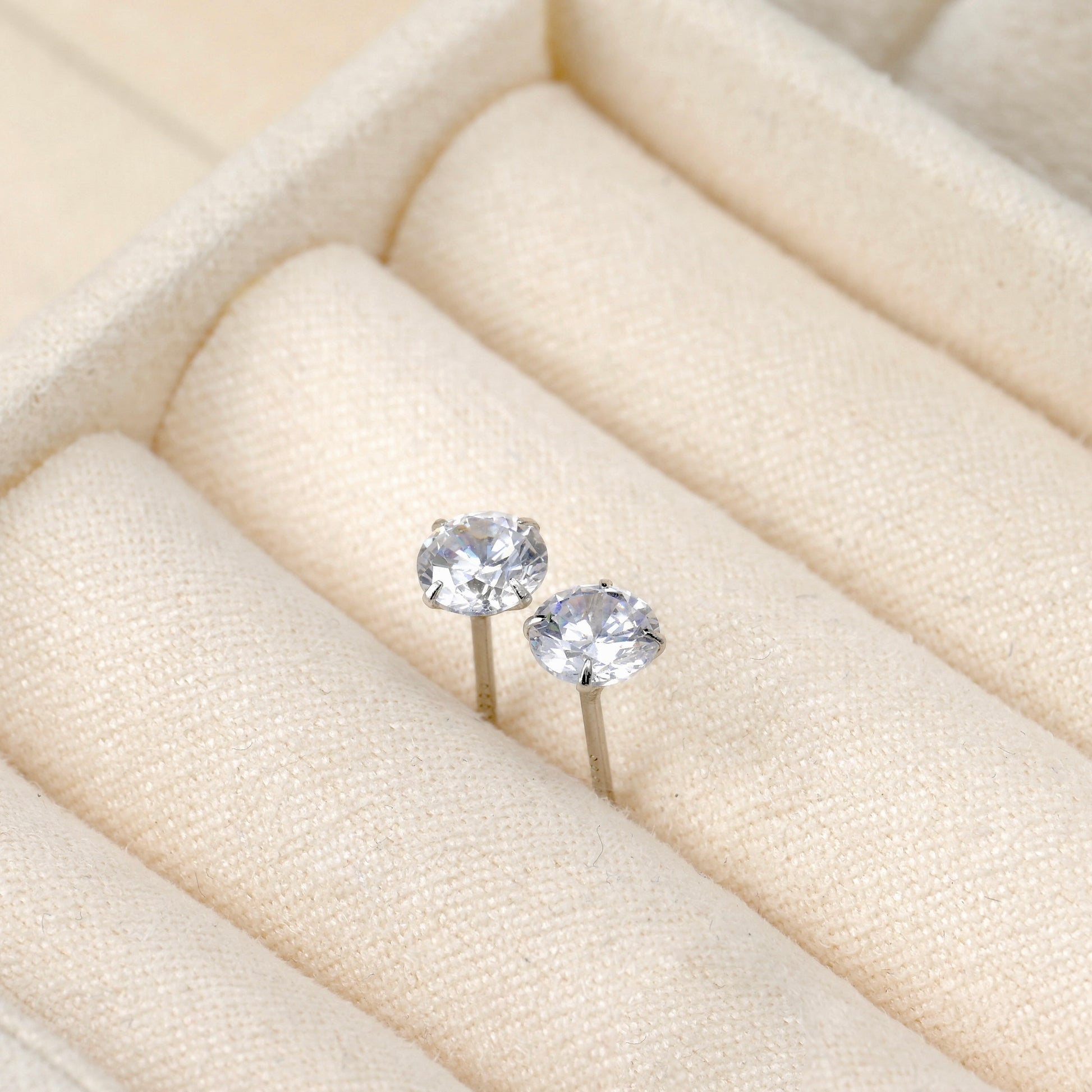 Pair of silver stud earrings on a soft beige ring tray.