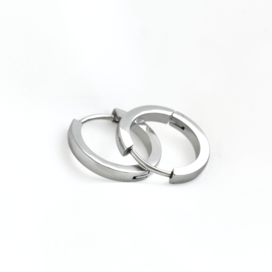 A pair of thin silver-toned metal hoop earrings with a polished finish, resting on a clean white background.