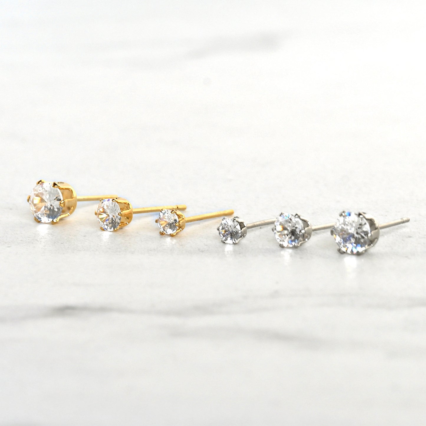 Front view of  gold and silver circle CZ earrings on gray marbel
