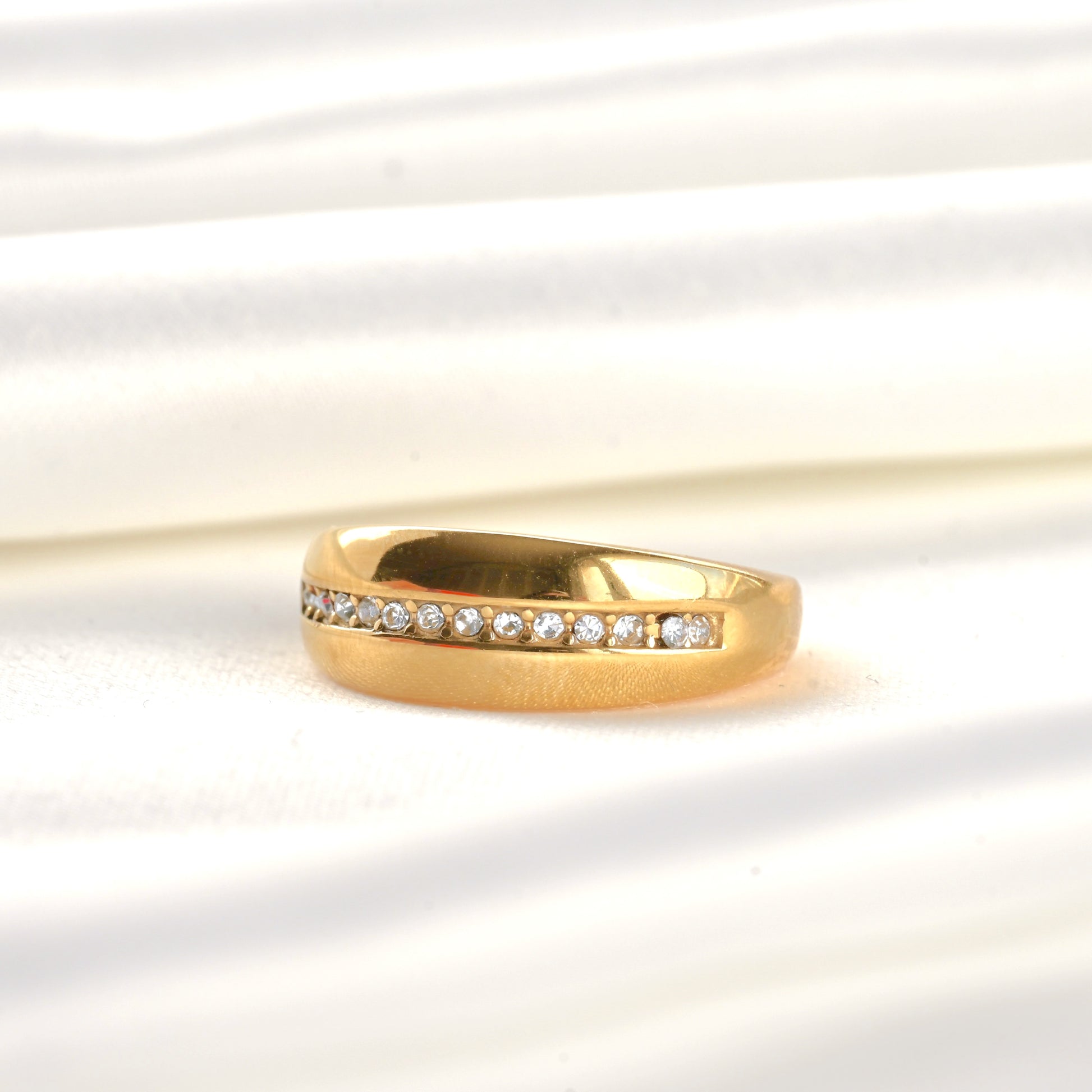 Gold diamond line ring with embedded CZ stones on a light background