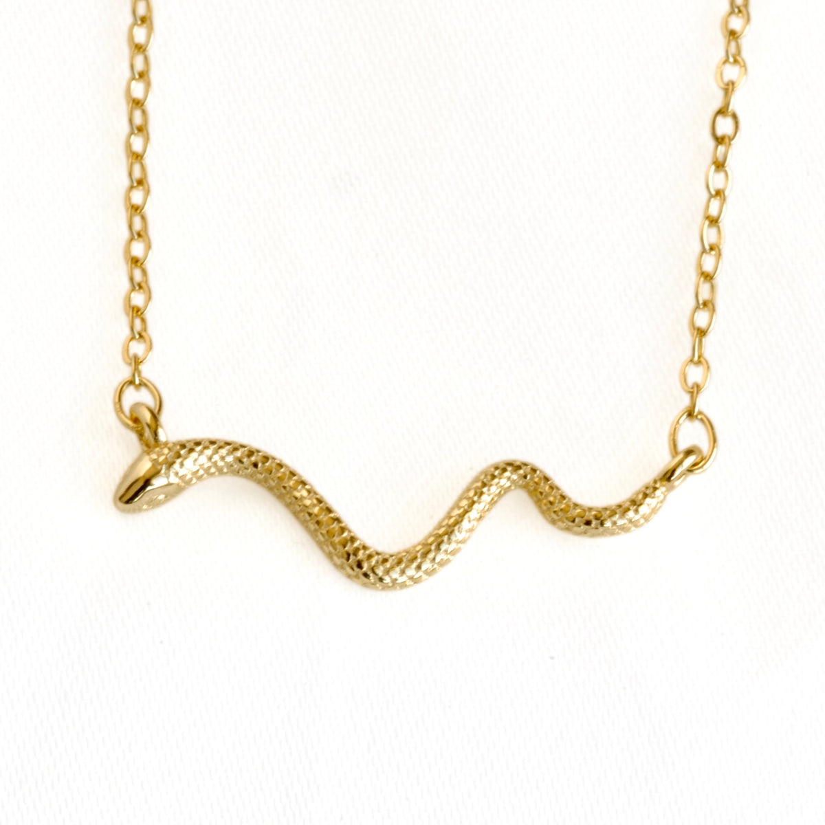 A gold snake pendant necklace with a textured scale finish, suspended from a delicate gold chain against a plain white background.