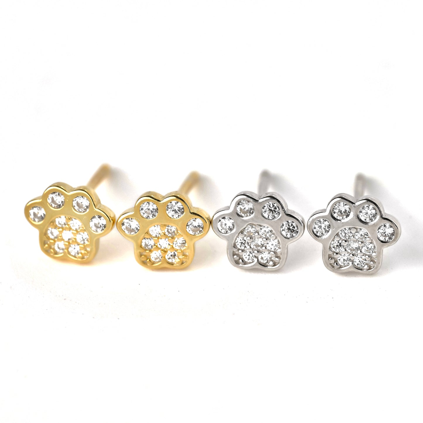 Pair of gold and silver paw-shaped earrings with clear CZ stones on a white background