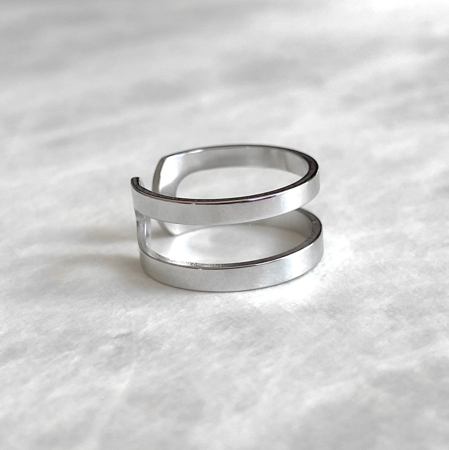 Side view of layered silver ring on a textured white surface