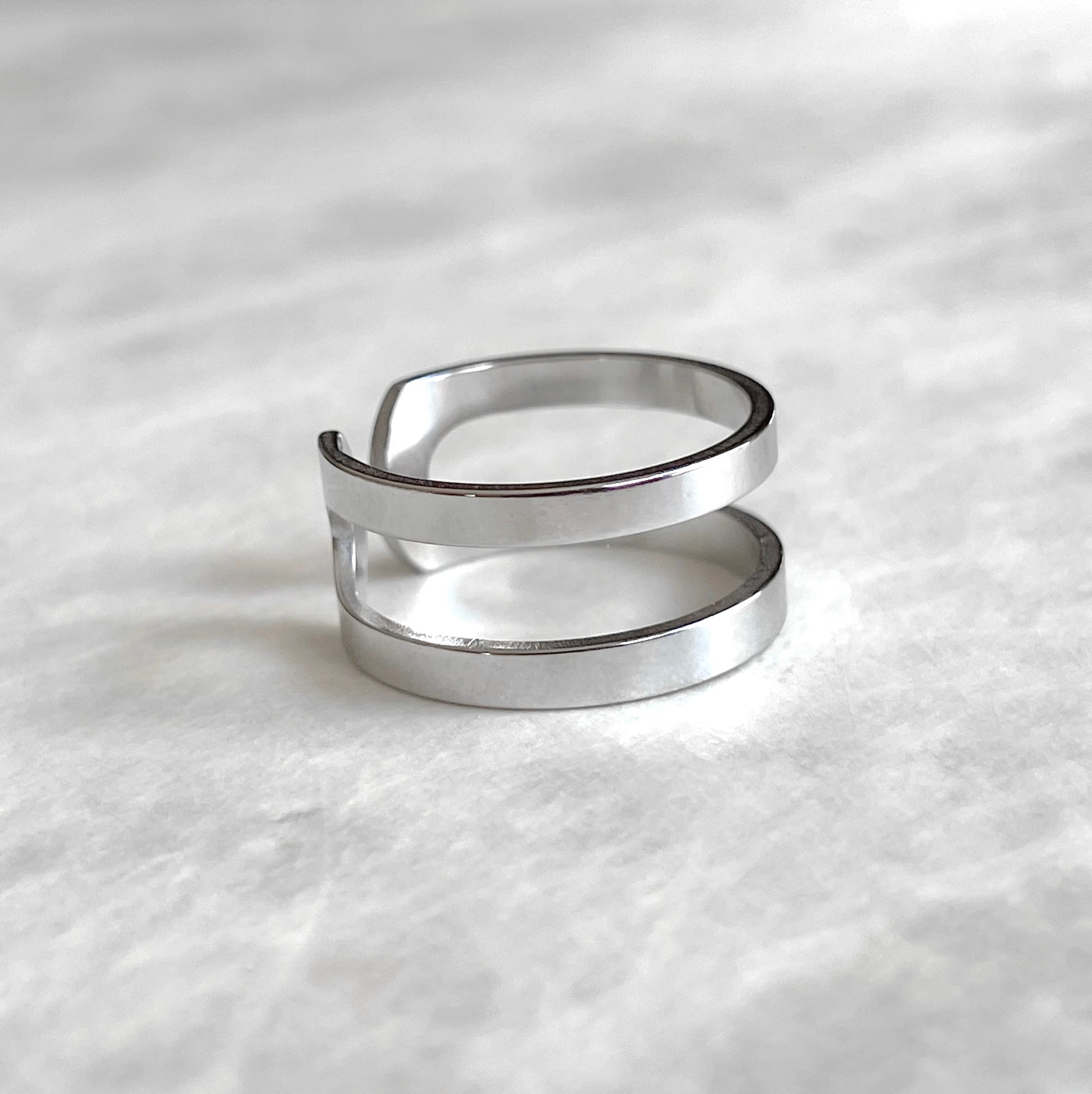 Side view of layered silver ring on a textured white surface