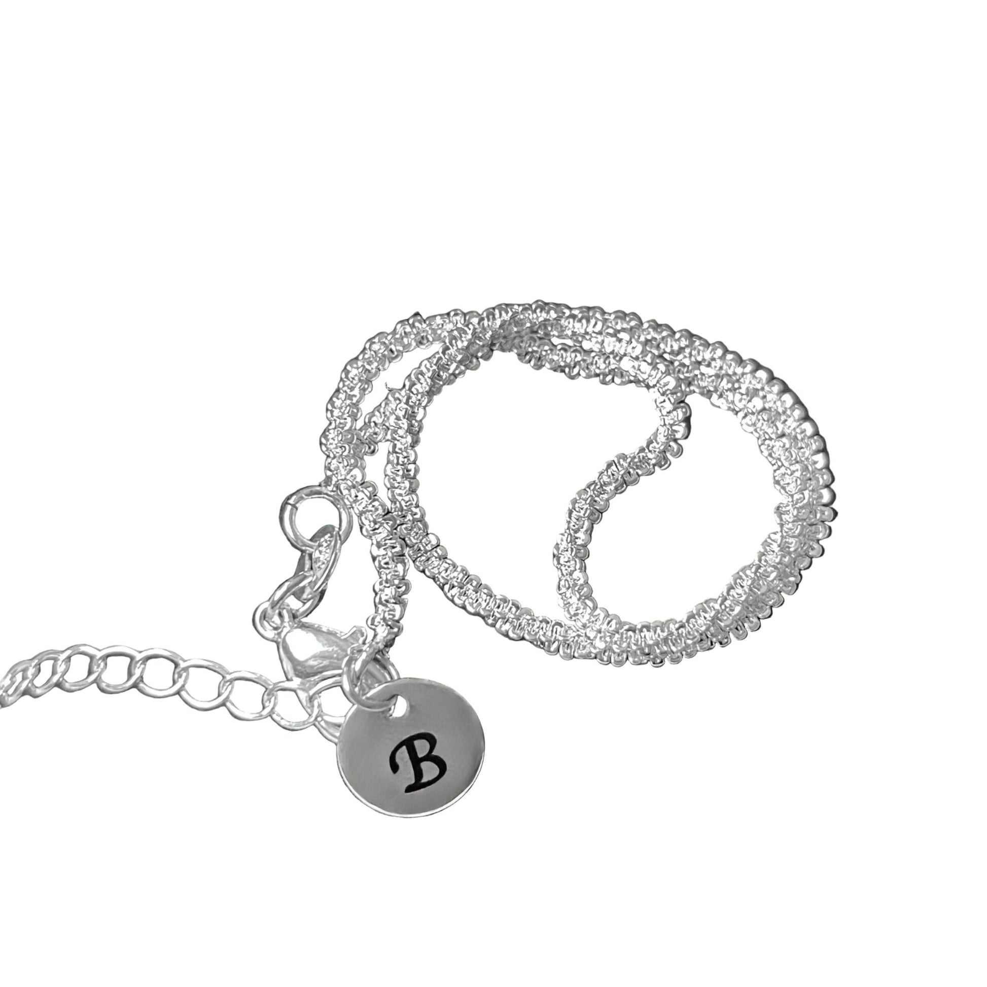 Silver ankle chain bracelet with a round charm featuring the letter 'B' on a white background
