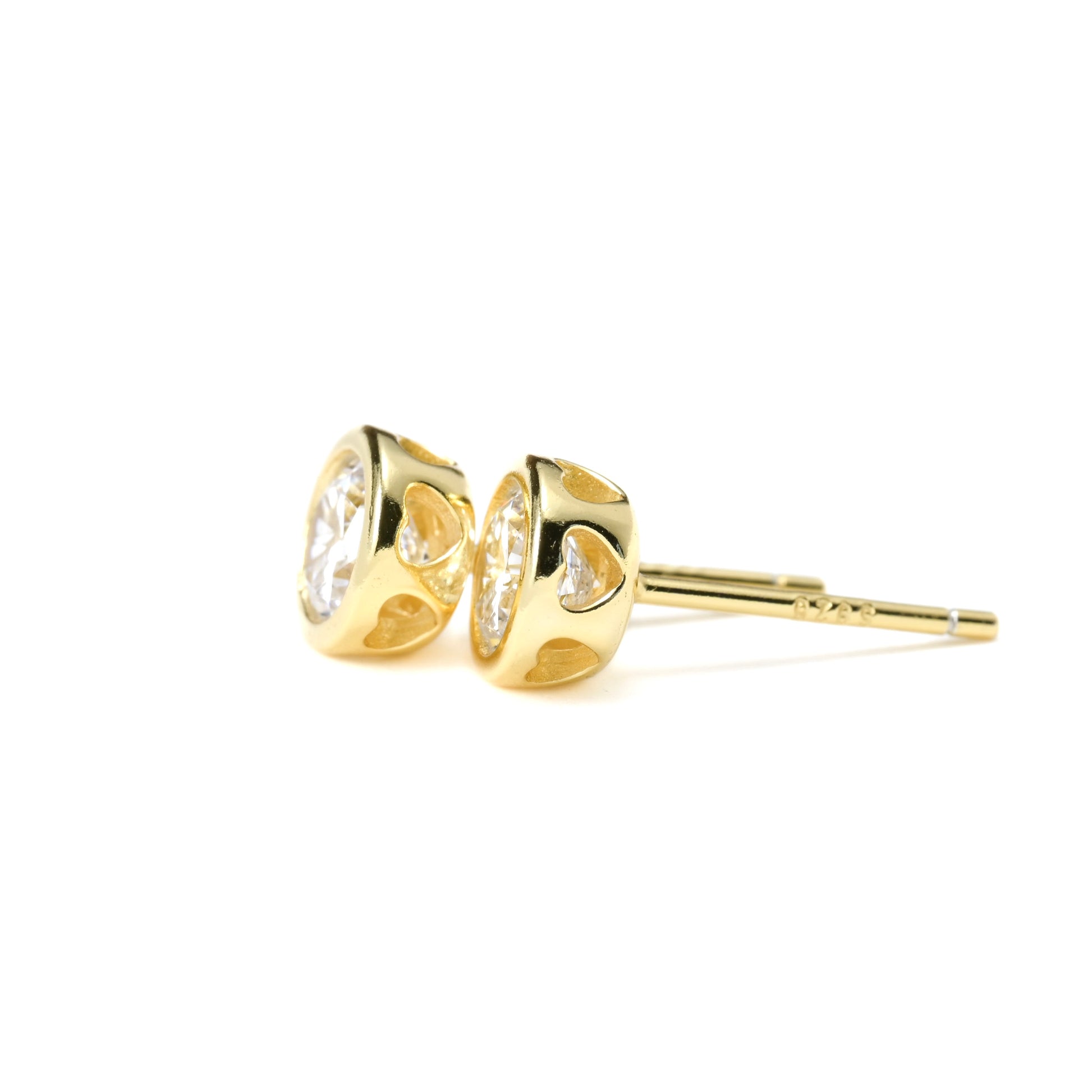 Small gold earrings with heart cut-outs on the sides of the basket on a white background