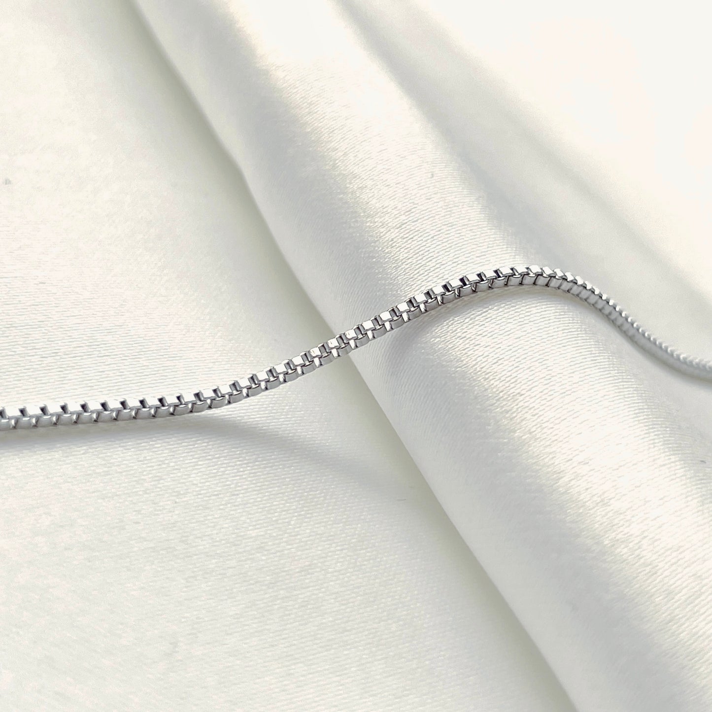 Side view of silver chain on a white fabric background