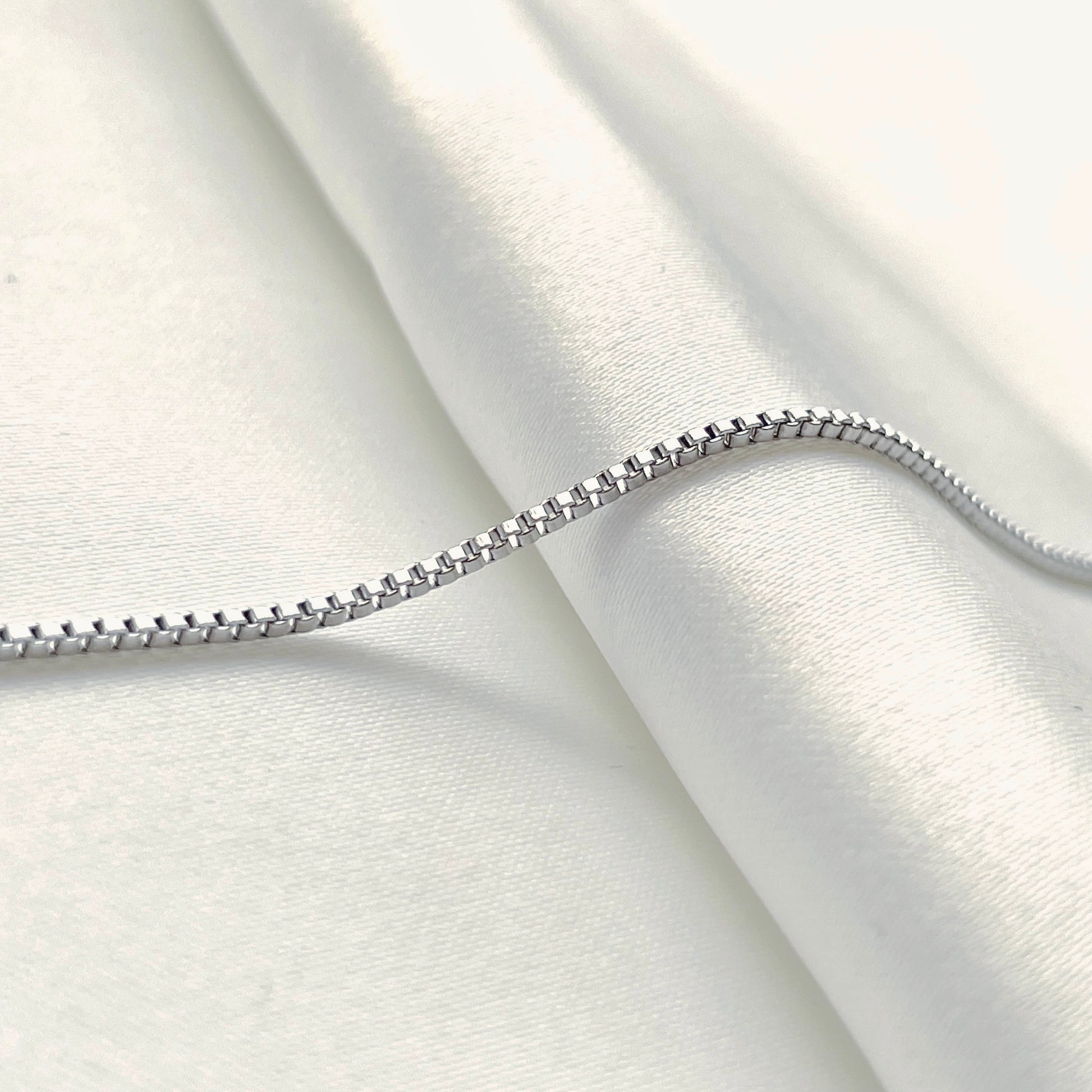 Side view of silver chain on a white fabric background