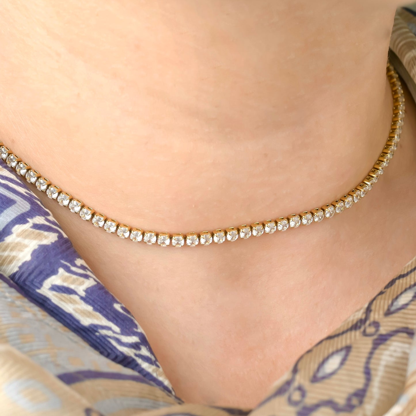 Close-up of a person wearing a 3mm  gold tennis chain with clear stones.