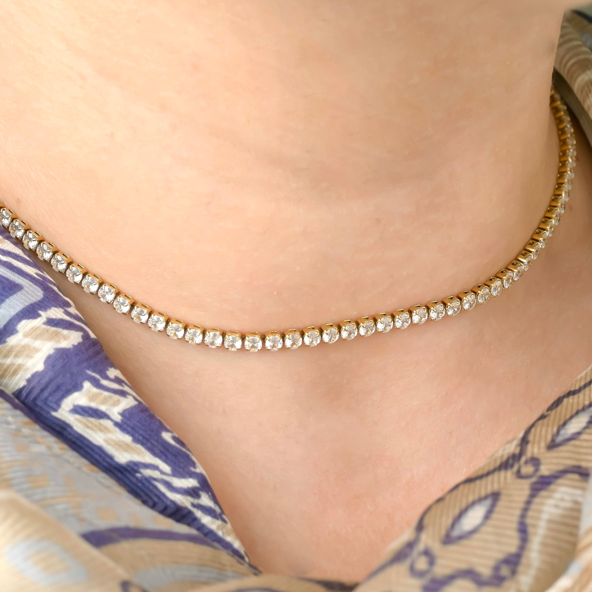 Close-up of a person wearing a 3mm  gold tennis chain with clear stones.