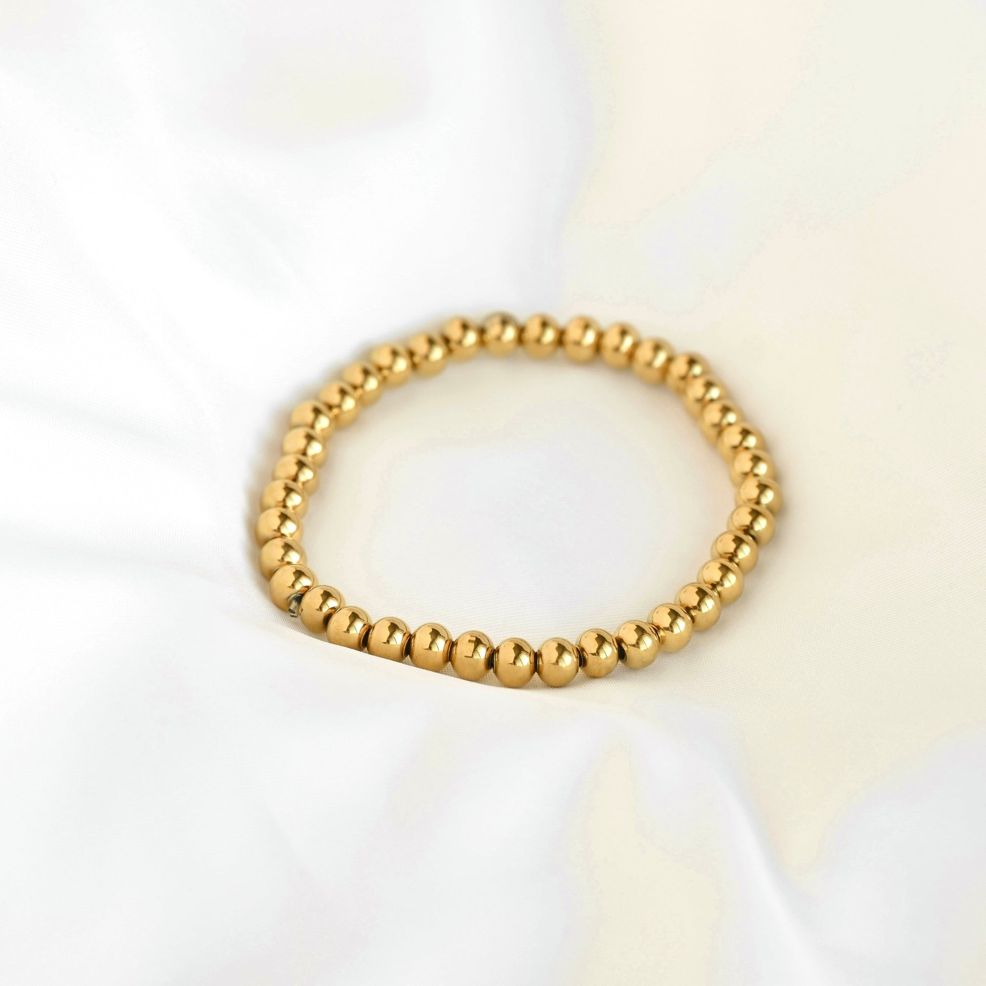 Gold ball stretch bracelet on a white background